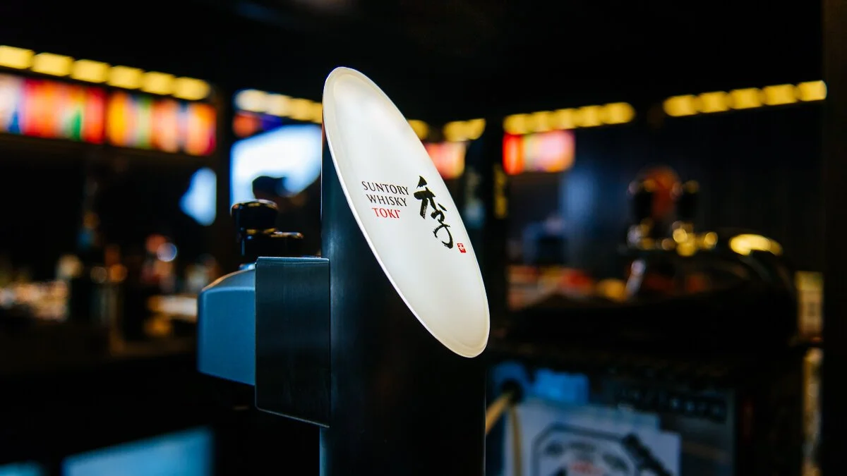 Close-up of a Suntory Whisky Toki tap dispenser in a dimly lit bar or restaurant setting.