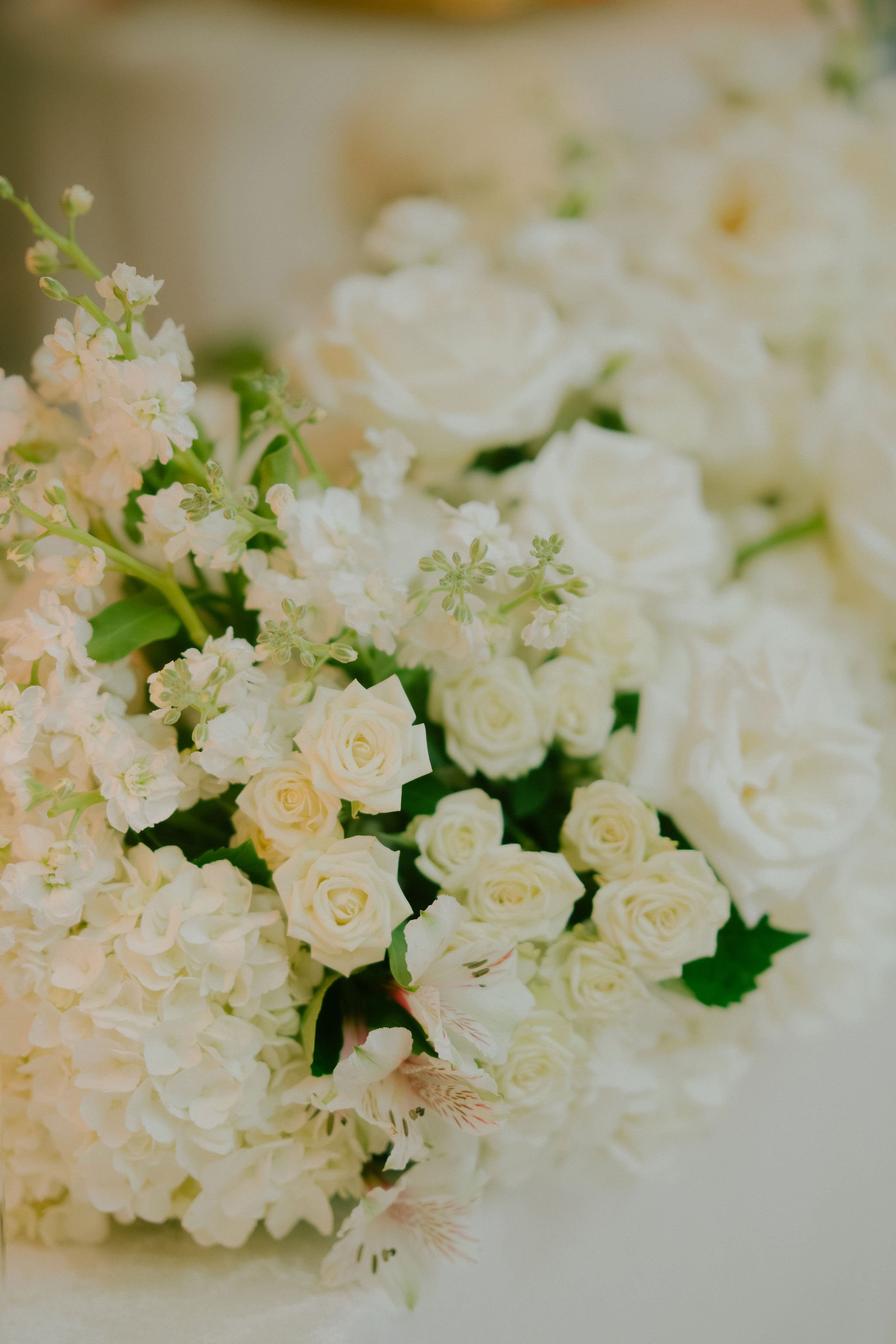 A close-up of a bouquet of white flowers including roses and other blooms.