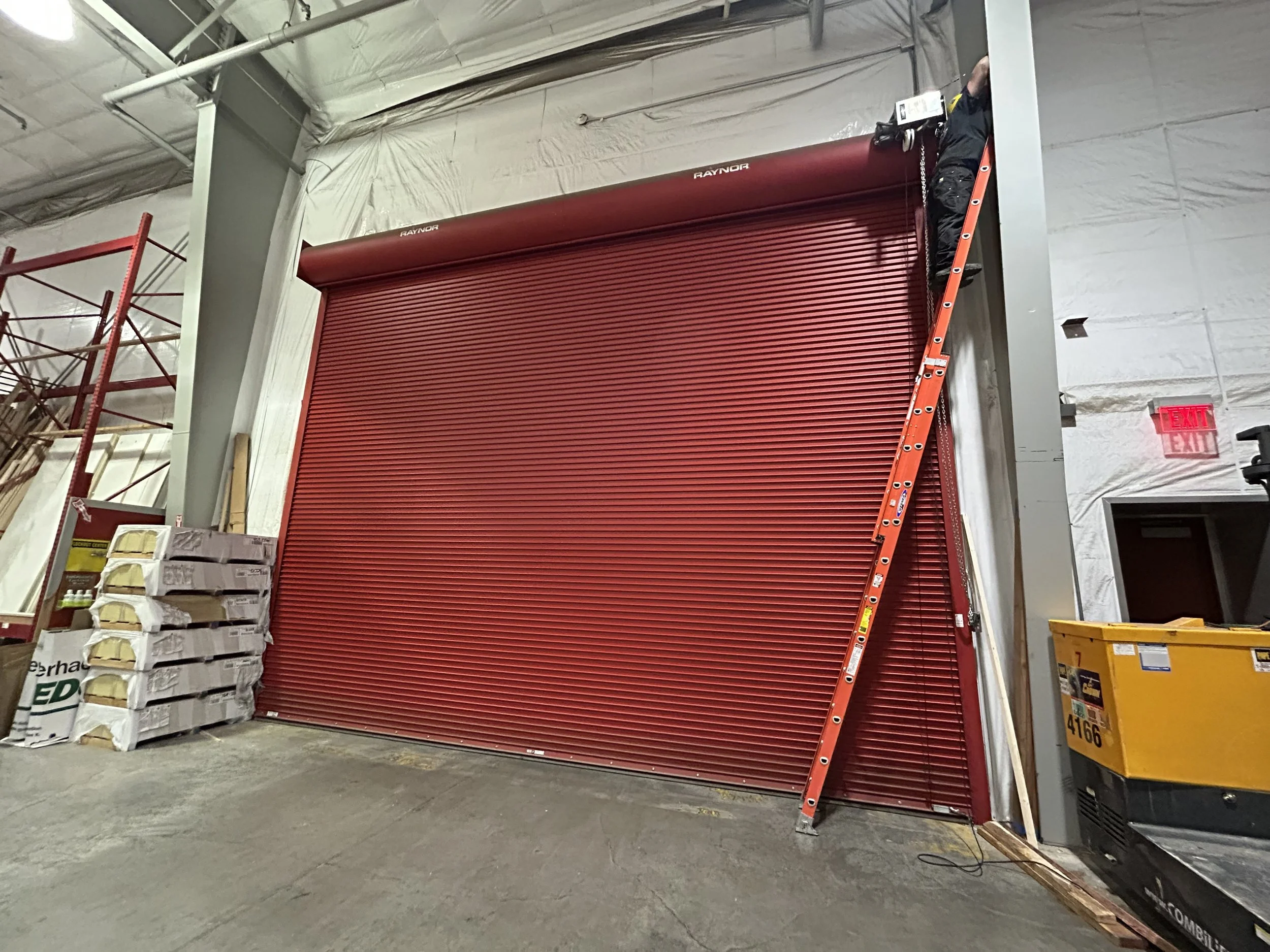 Red fire door being inspected by R&S technician on a ladder