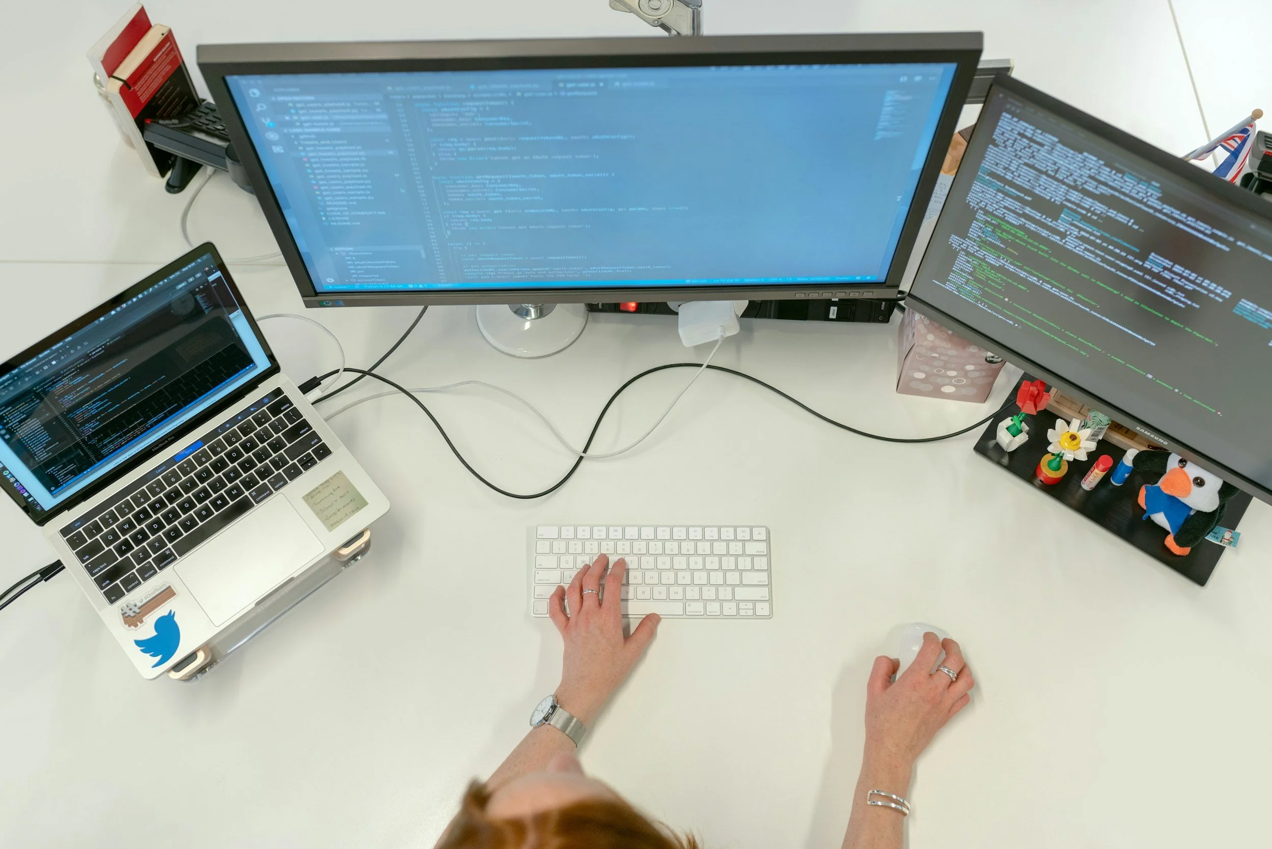 Woman sitting behind a desk with a laptop computer and a desktop computer with two screens