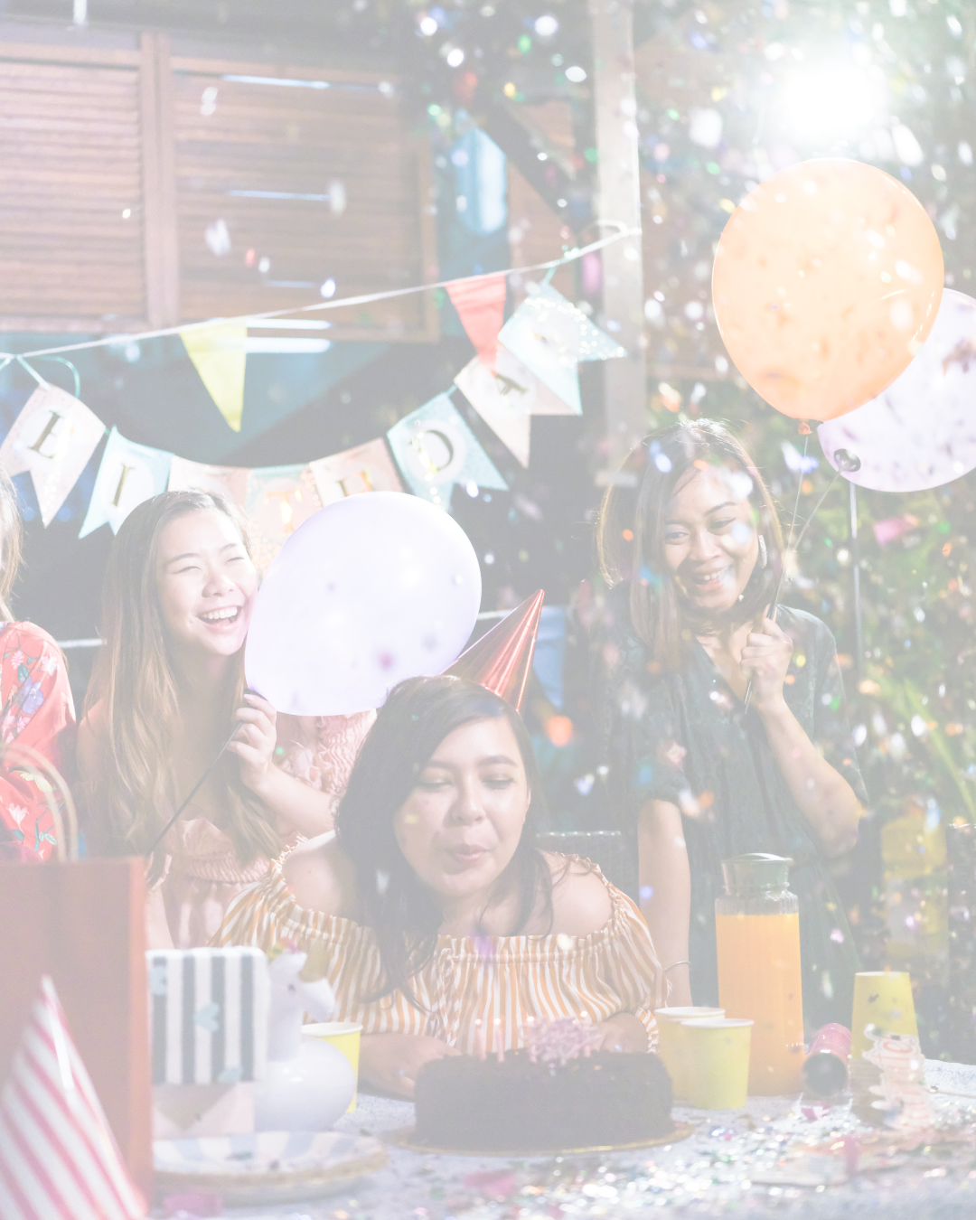 Celebrating a birthday with friends, balloons, party hats, and a chocolate cake at a decorated outdoor party.