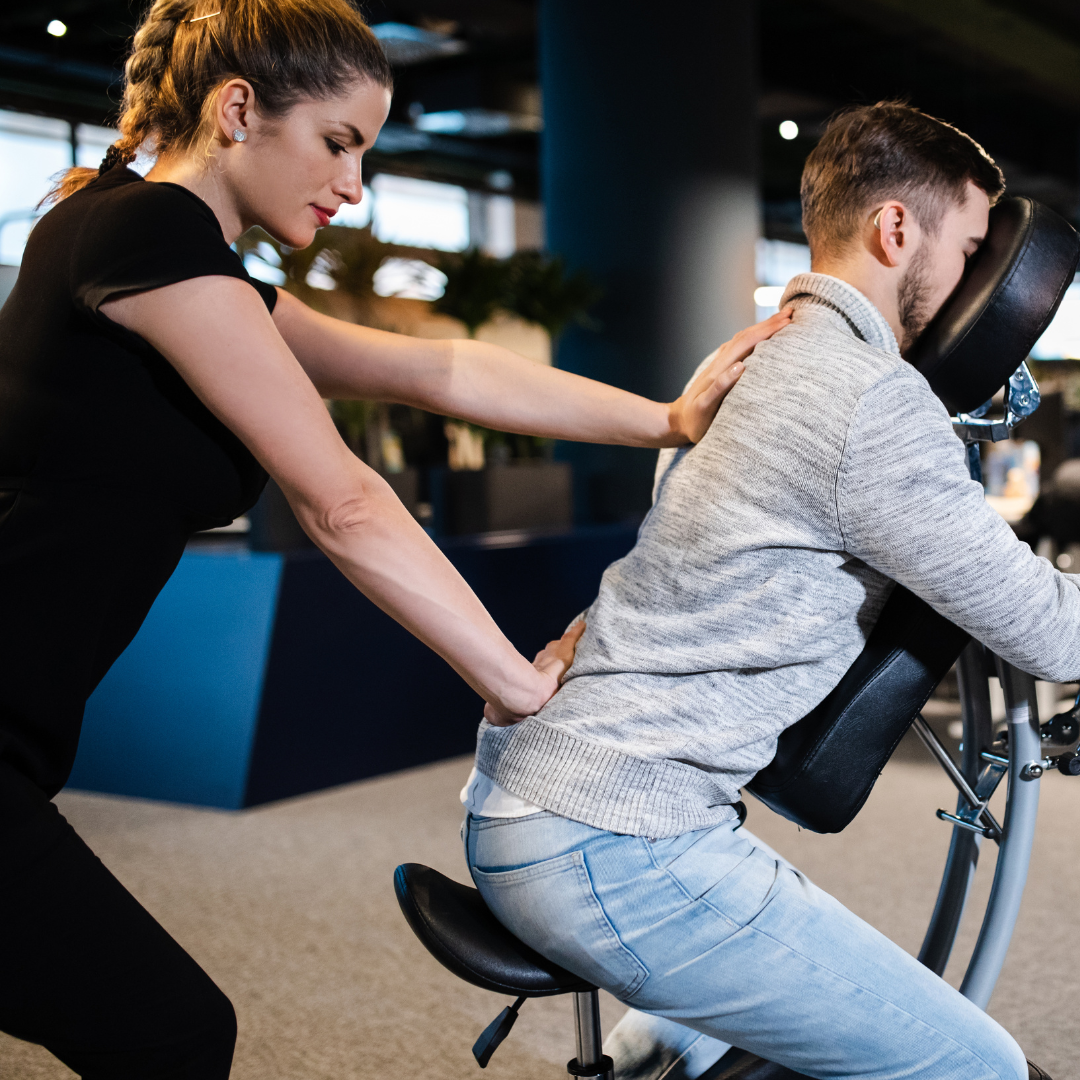A Balanced Pro Massage therapist wearing black giving a tech employee a seated massage