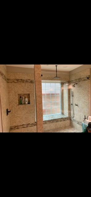 Luxury marble-tiled walk-in shower with glass enclosure, rain showerhead, handheld sprayer, built-in niche, and large window