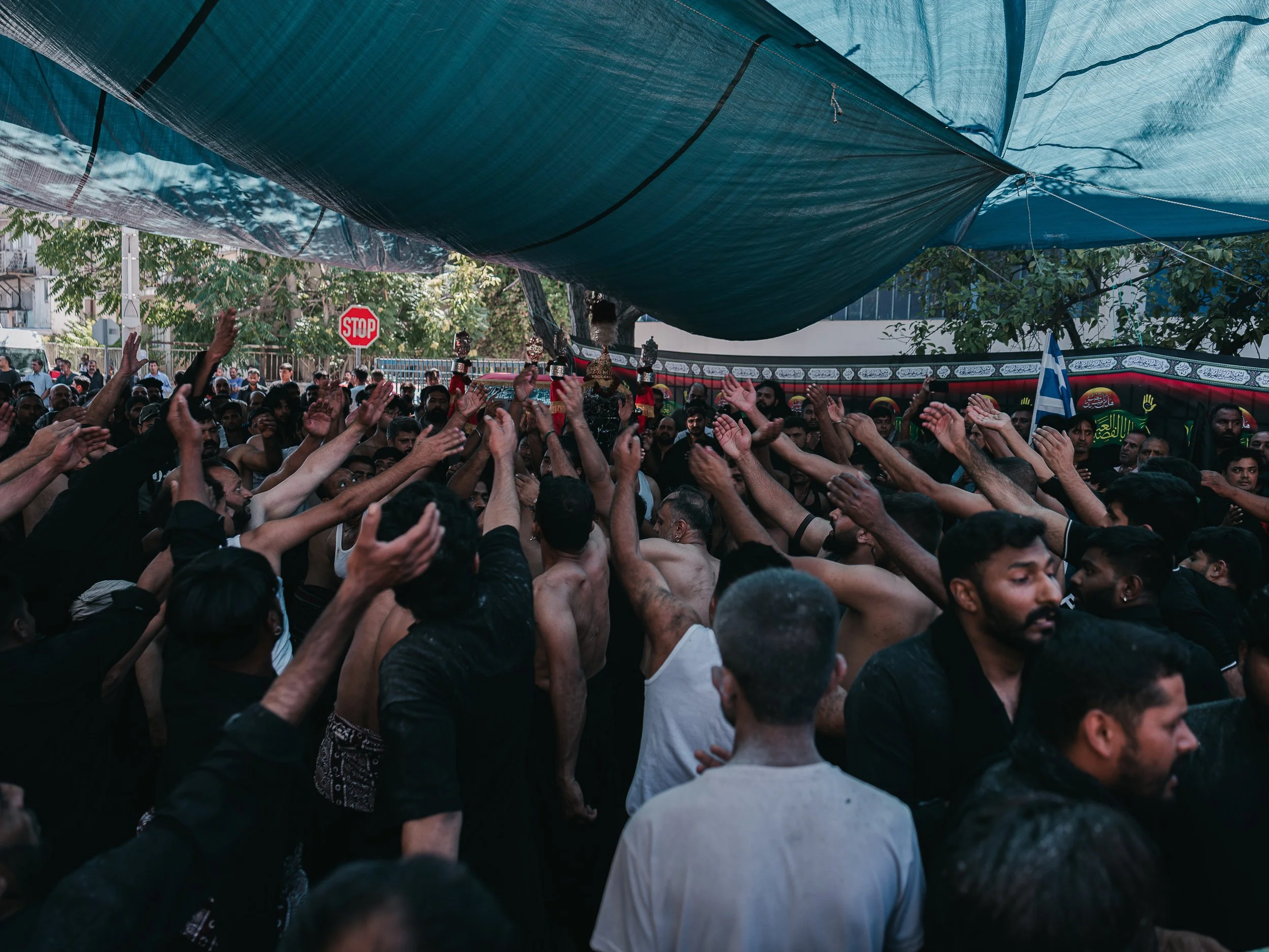 Men raise their hands and perform rhythmic chest-beating beside the self-organized Shi’a mosque in Peristeri, Athens, Greece on July 6, 2025. The ritual, called latm or matam, involves men chanting elegies while striking their chests in unison to mou