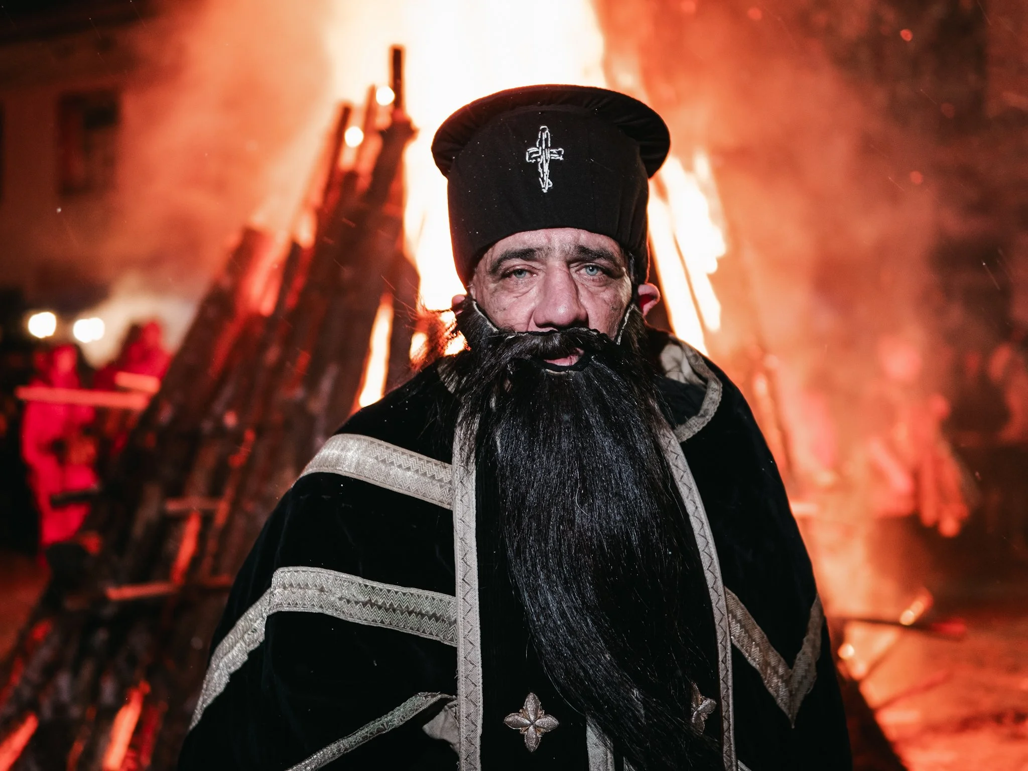 n the early Surva traditions, roles such as the woman’s character were also performed by men. Here, a man dressed in traditional women's clothing, playfully sticking out his tongue, stands before a group of three women and another man, embodying the 