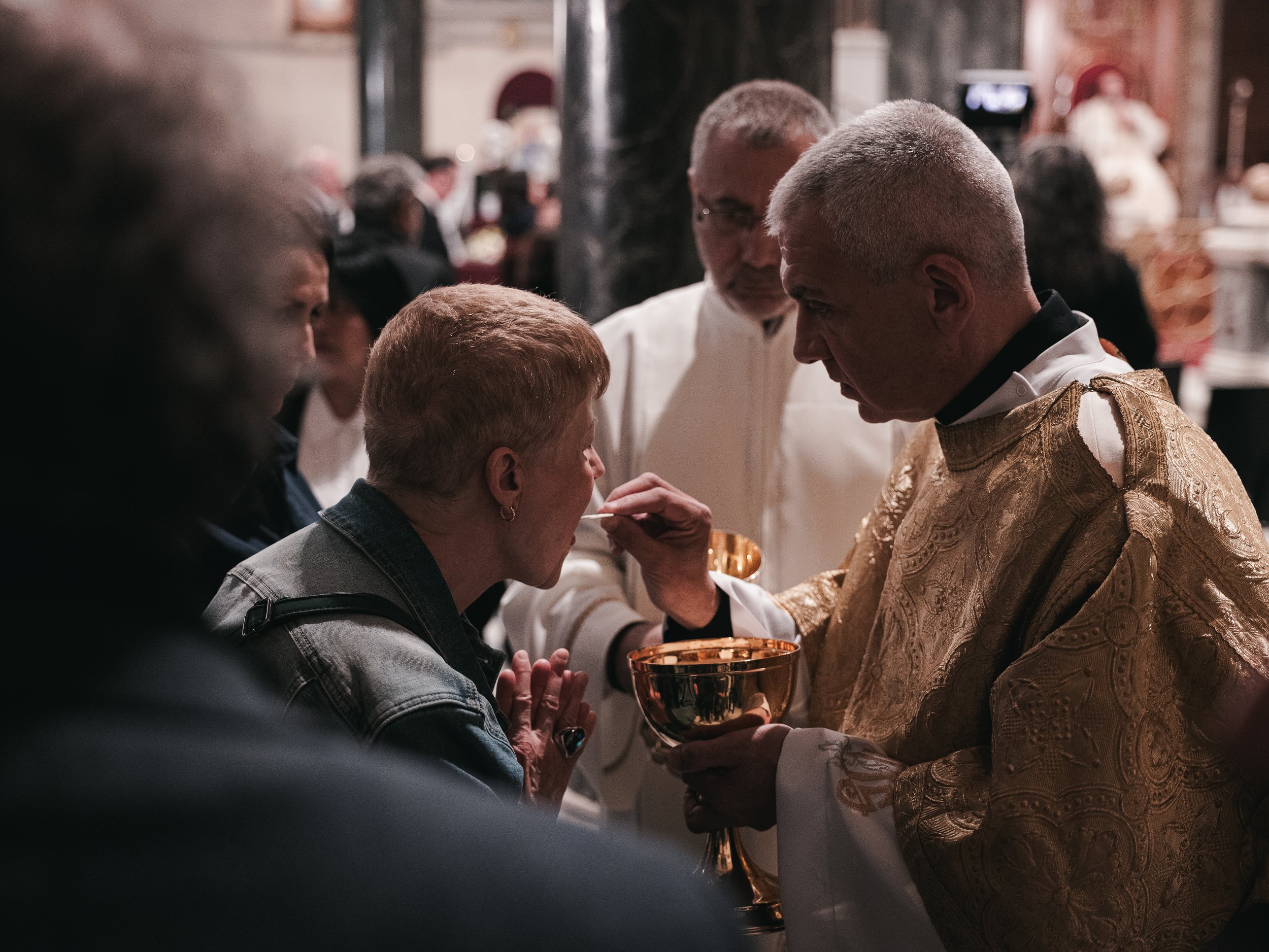 A woman receives antidoron (blessed bread) from a priest following a prayer service for the late Pope Francis at the Basilica of Saint Dionysius in central Athens.