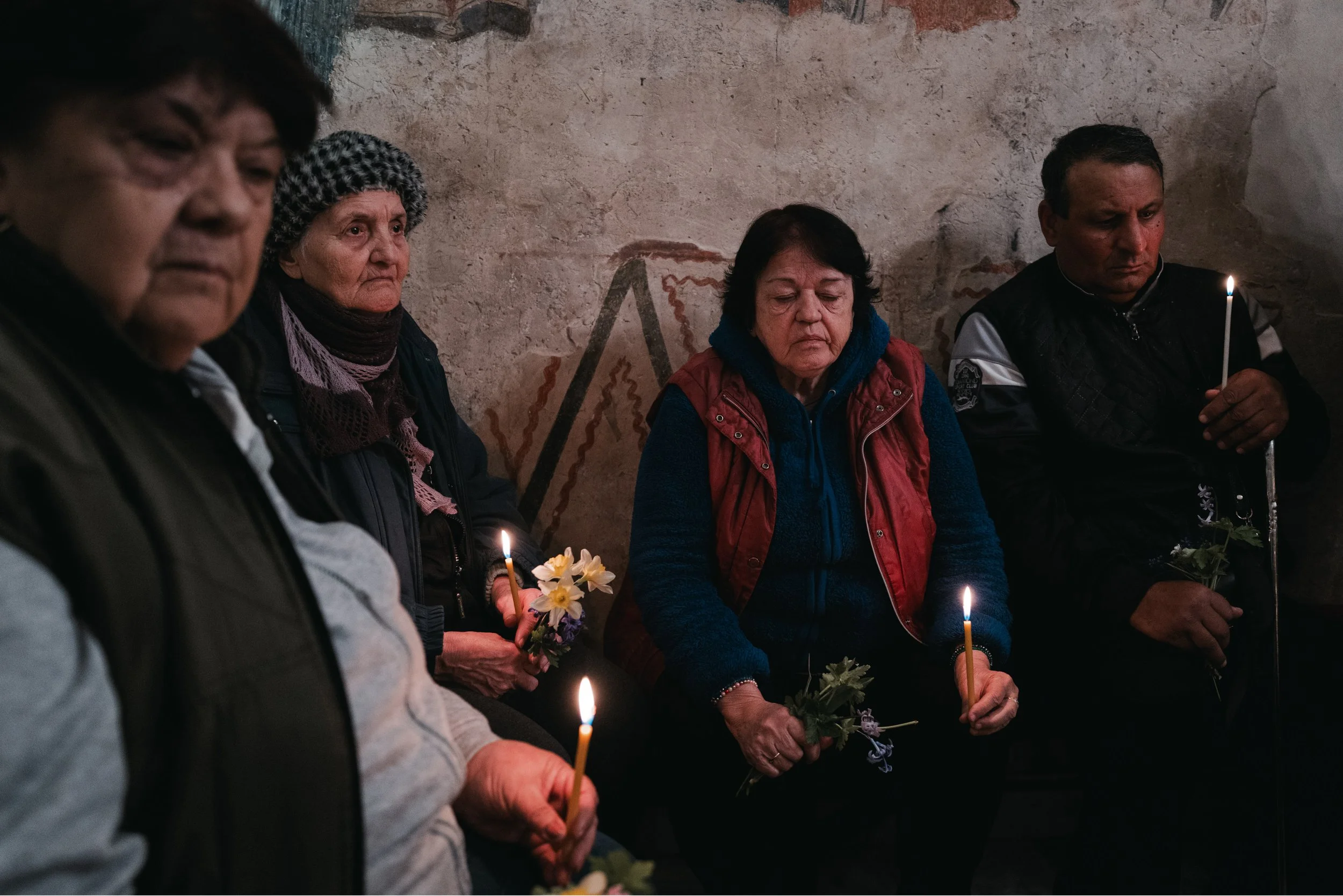 Believers sit holding flowers after they have been distributed while listening to the liturgy in Iskrets, Bulgaria on April 10, 2026. The scene is part of the Orthodox Good Friday service, reflecting mourning, prayer, and remembrance of the burial of