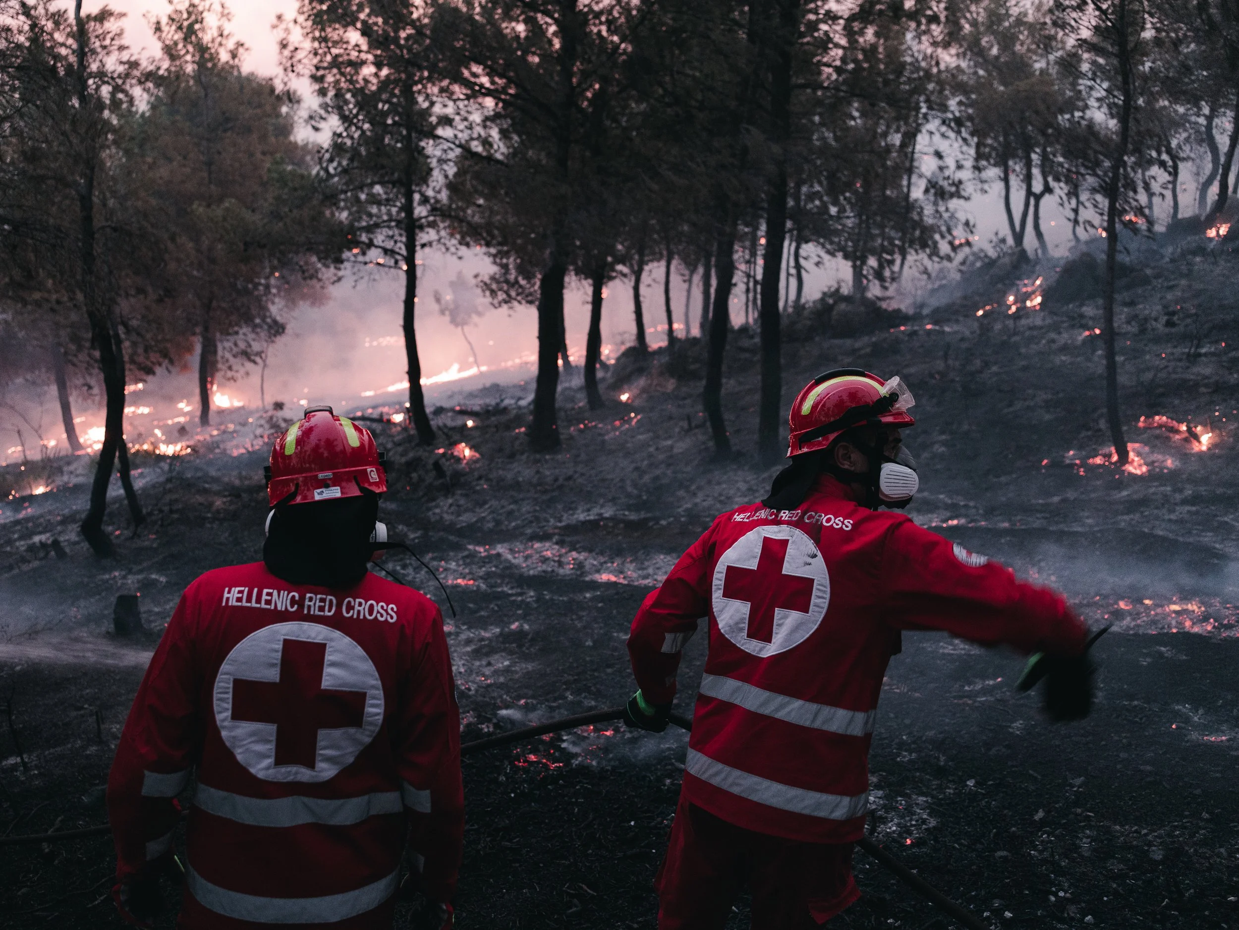 Red Cross volunteers assist in extinguishing a wildfire in a forested ravine near Asprohori, as emergency crews battle fast-moving flames in northeastern Attica, in Asprohori on July 9, 2025.