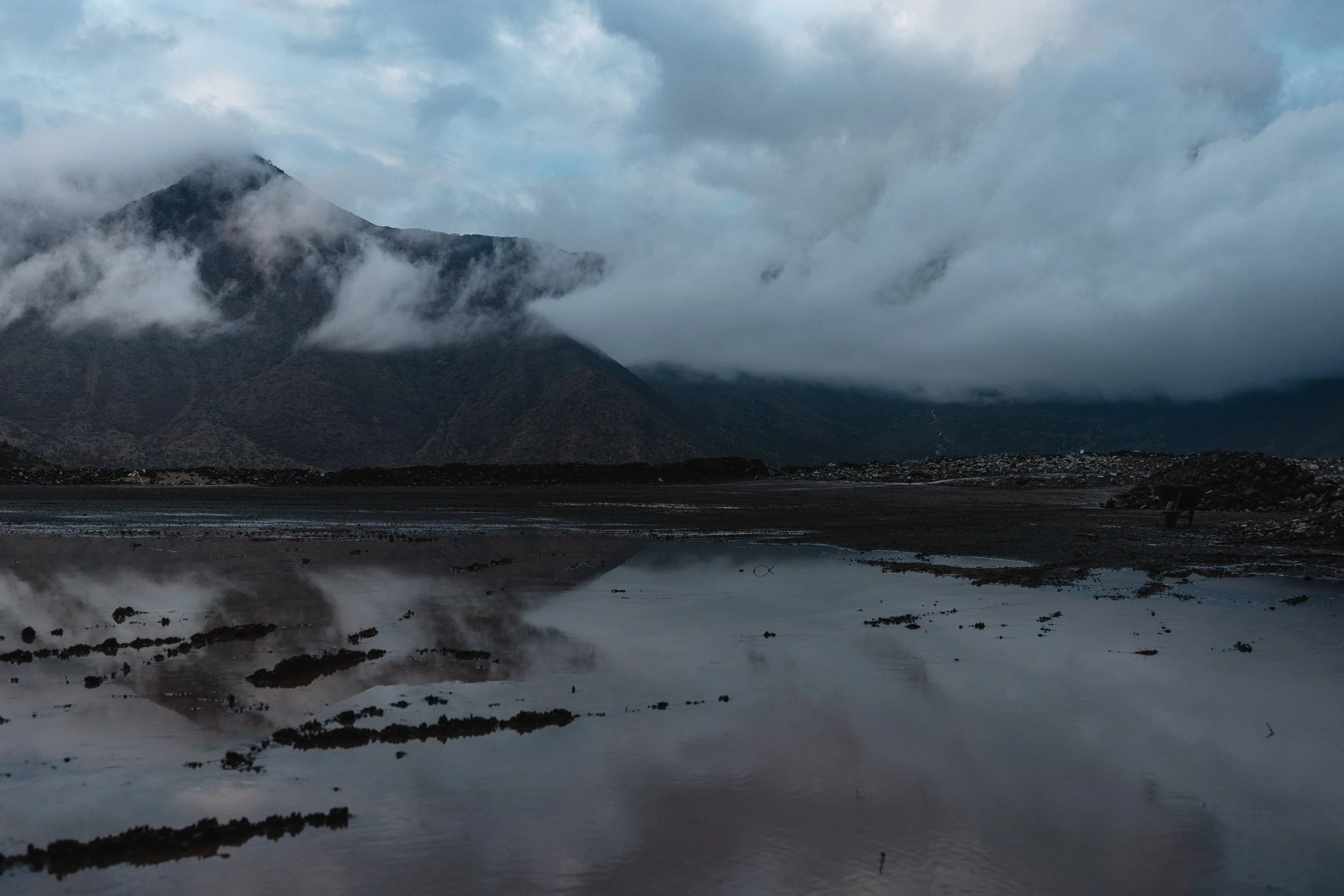 A landscape taken from the mine shows pools of water on the ground with the mountain visible in front in Bulqizë, Dibër County, Albania on November 11, 2025. The image captures the mining terrain and natural surroundings of one of Europe’s largest ch