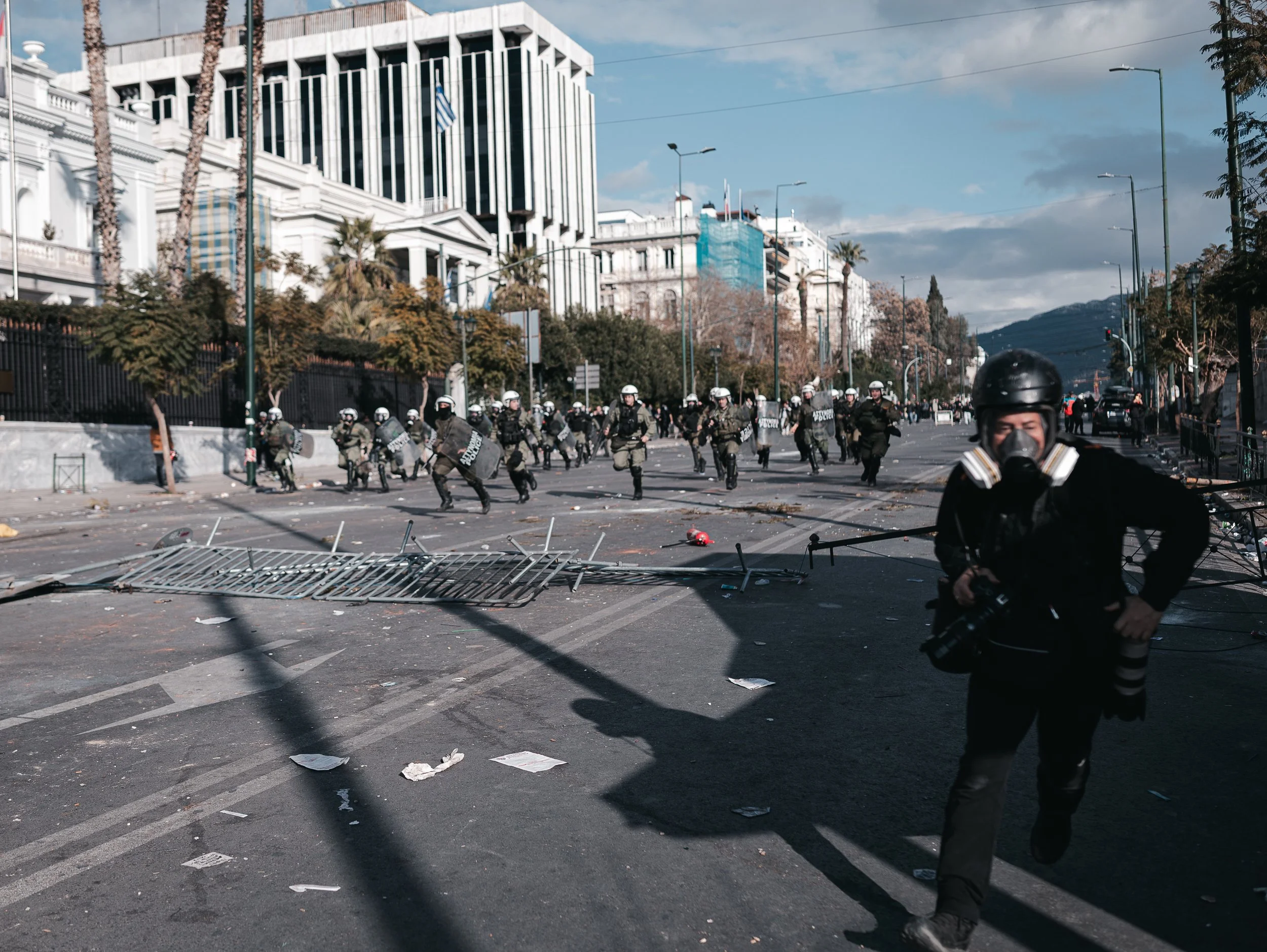 A photojournalist flees during clashes between protesters and police in Athens on February 28, 2025