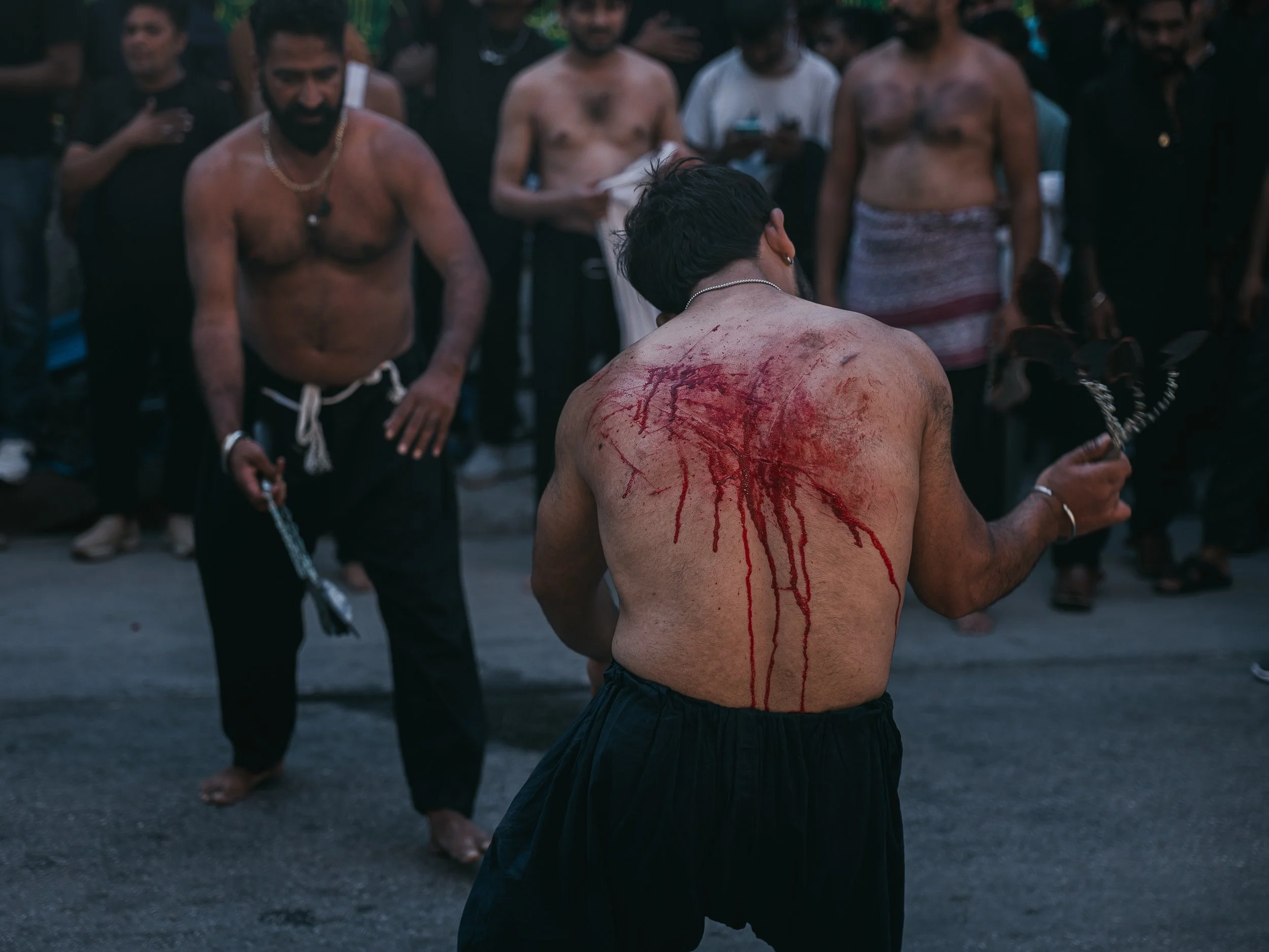 Men strike themselves beside the self-organized Shi’a mosque in Peristeri, Athens, Greece on July 6, 2025. The act is part of an Ashura self-flagellation ritual performed by some Shi’a groups to mourn the martyrdom of Imam Husayn at Karbala.