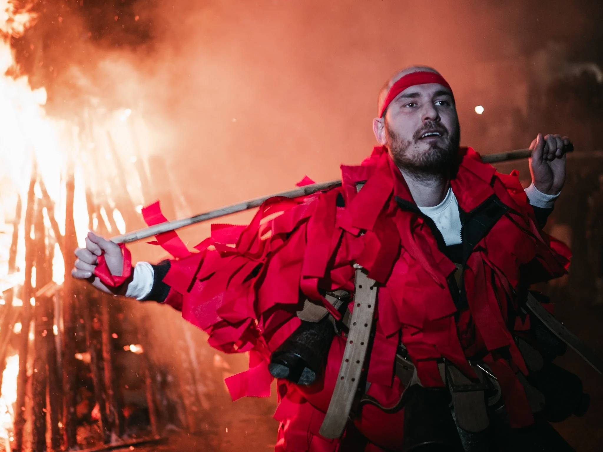 A man, holding a torch over his shoulder, performs a traditional dance next to the Surva fire in Kosharevo, embodying the festival's ritualistic energy meant to protect the community and ensure good fortune in the coming year.