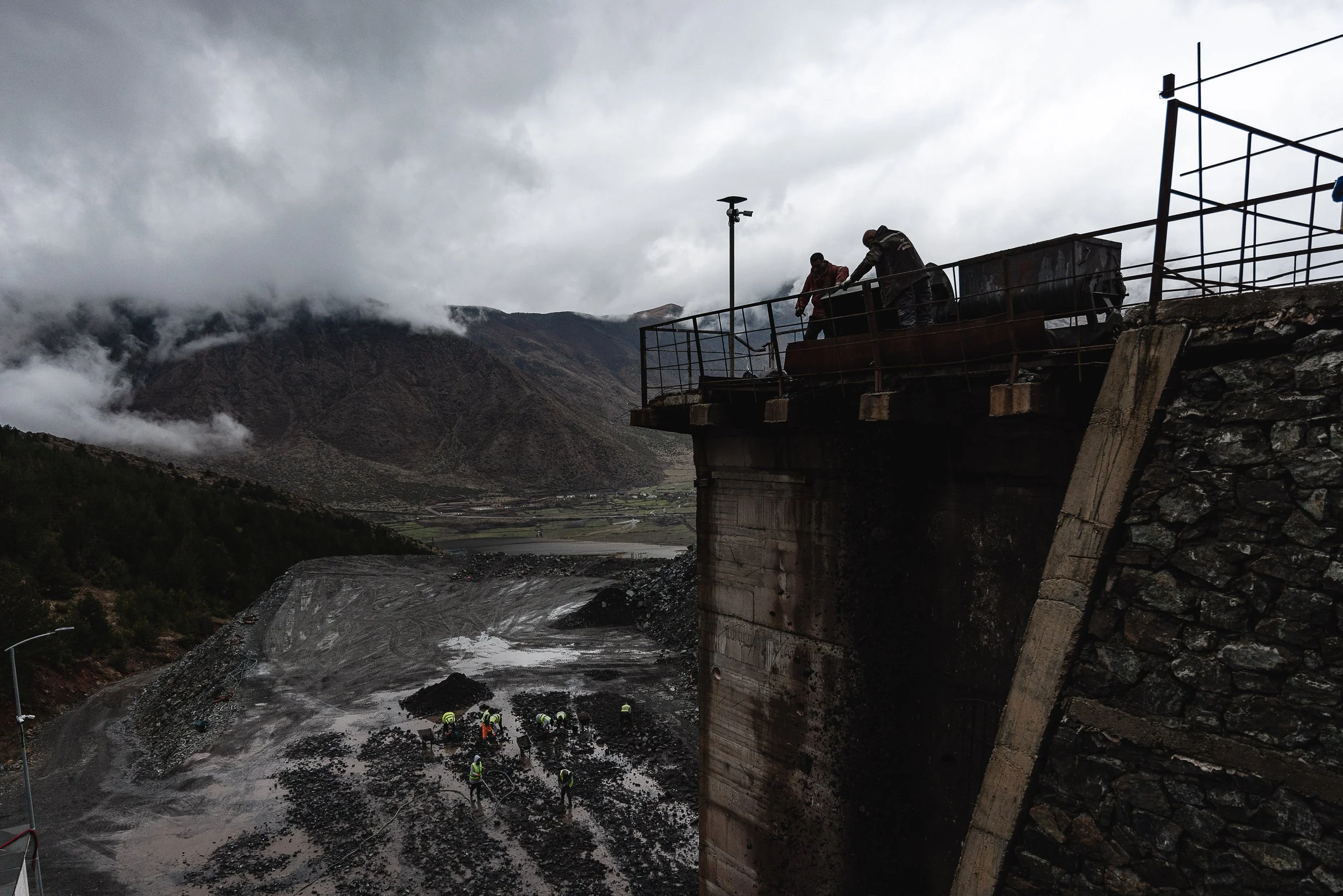Men push a small mine cart filled with extracted chromium toward the processing area in front of the mine in Bulqizë, Dibër County, Albania on November 11, 2025. The activity shows the hands-on labor involved in transporting ore for further processin