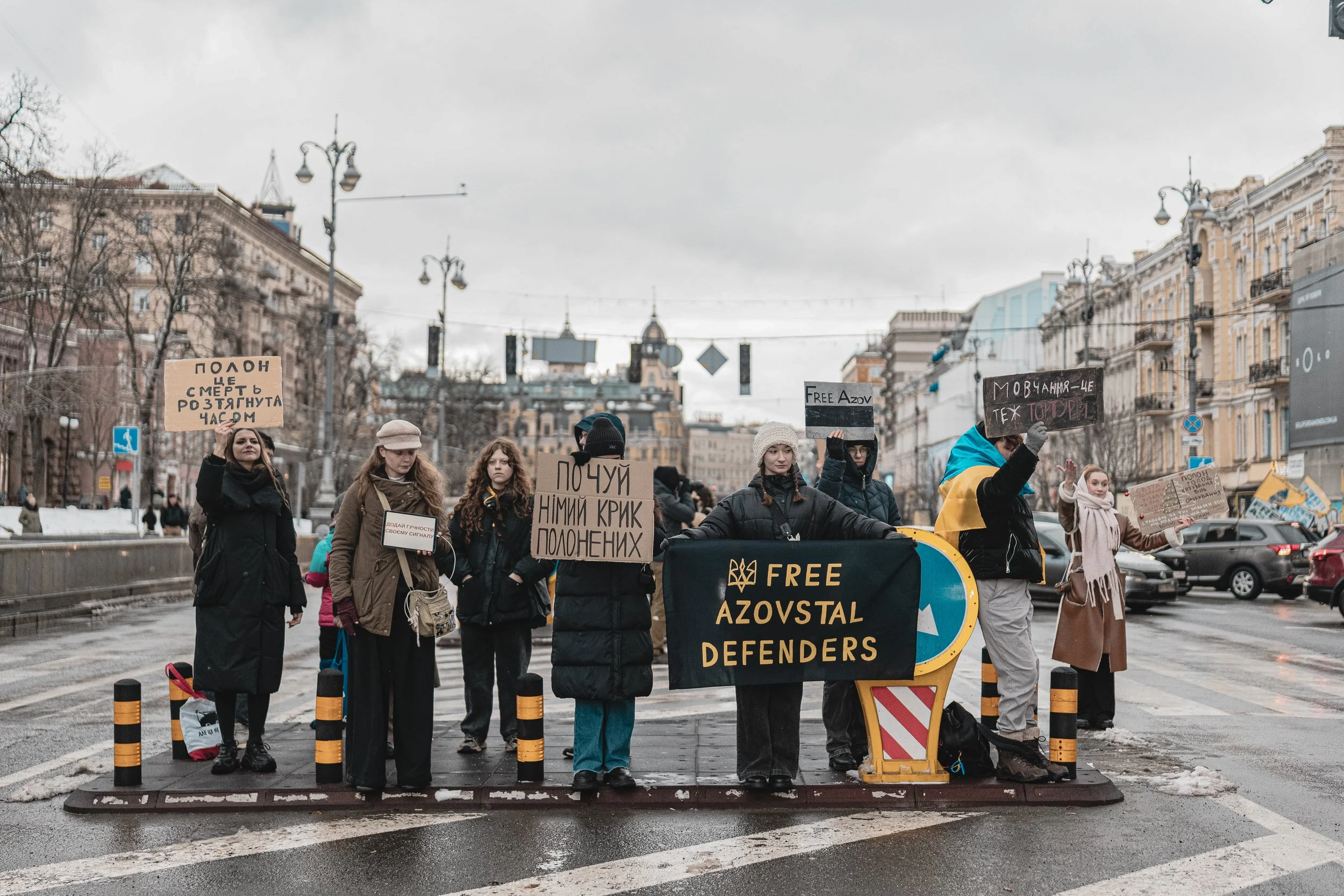 A girl holds a large banner reading Free Azovstal Defenders at the intersection of Khreshchatyk and Bohdan Khmelnytsky Streets in Kyiv, Ukraine on December 28, 2025. The gathering brings together families, friends, and citizens to show solidarity wit