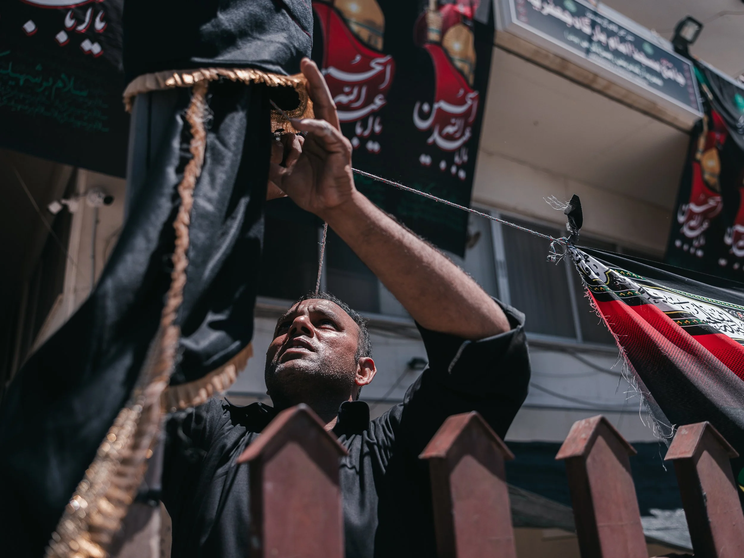 A man places a flag on the fence outside the self-organized Shi’a mosque in Peristeri, Athens, Greece on July 6, 2025. The act is part of the Ashura preparations, marking the commemoration of Imam Husayn’s martyrdom.