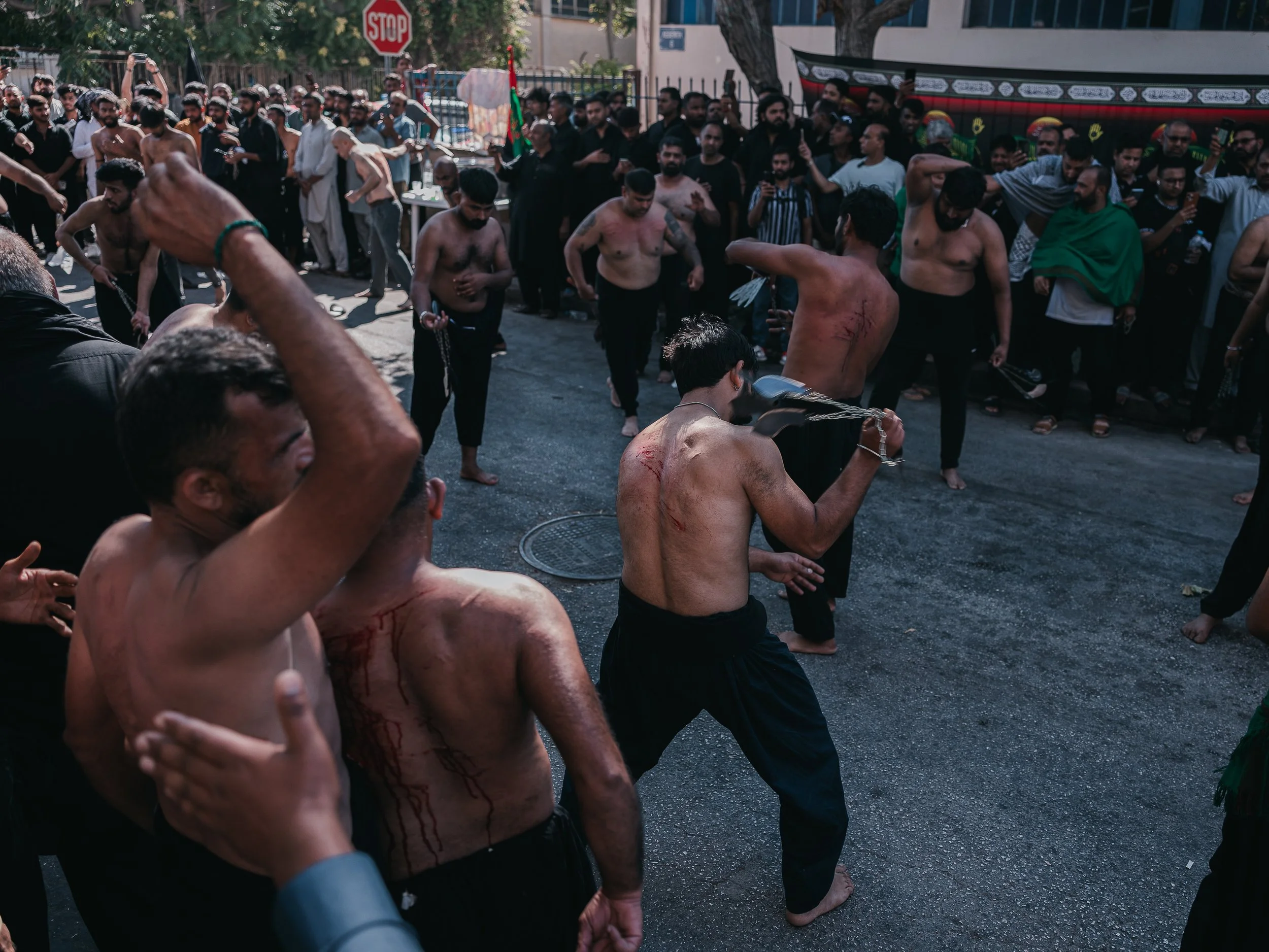 Men strike themselves beside the self-organized Shi’a mosque in Peristeri, Athens, Greece on July 6, 2025. The act is part of an Ashura self-flagellation ritual performed by some Shi’a groups to mourn the martyrdom of Imam Husayn at Karbala