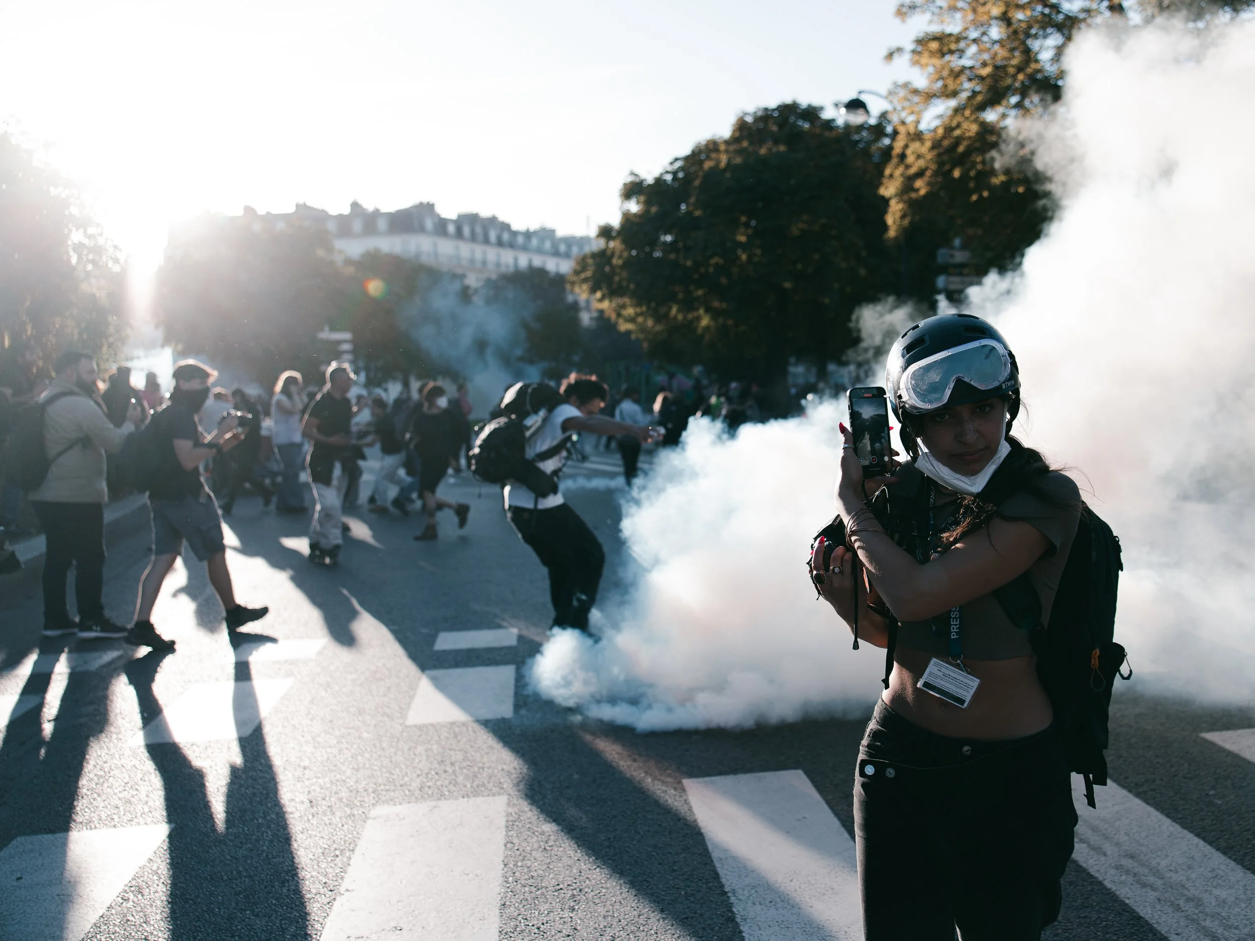A journalist flees as French police deploy tear gas and a protester tries to kick the grenade during clashes in Paris, France, on September 18, 2025.