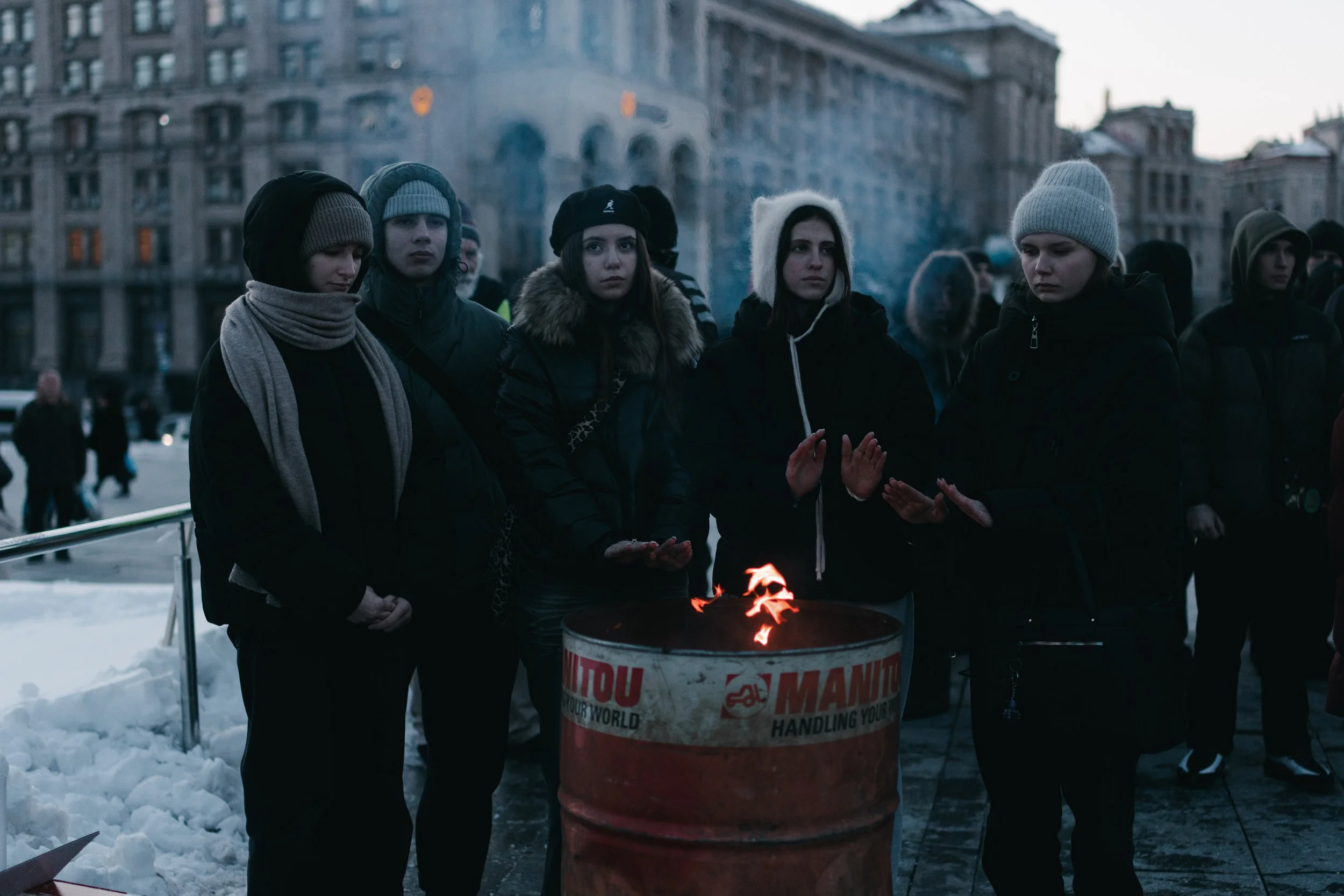 Young boys and girls warm themselves by an improvised fire during the memorial artistic program at Maidan Nezalezhnosti in Kyiv on February 20, 2026. The program is part of the commemorations for the Day of the Heavenly Hundred Heroes organized by th
