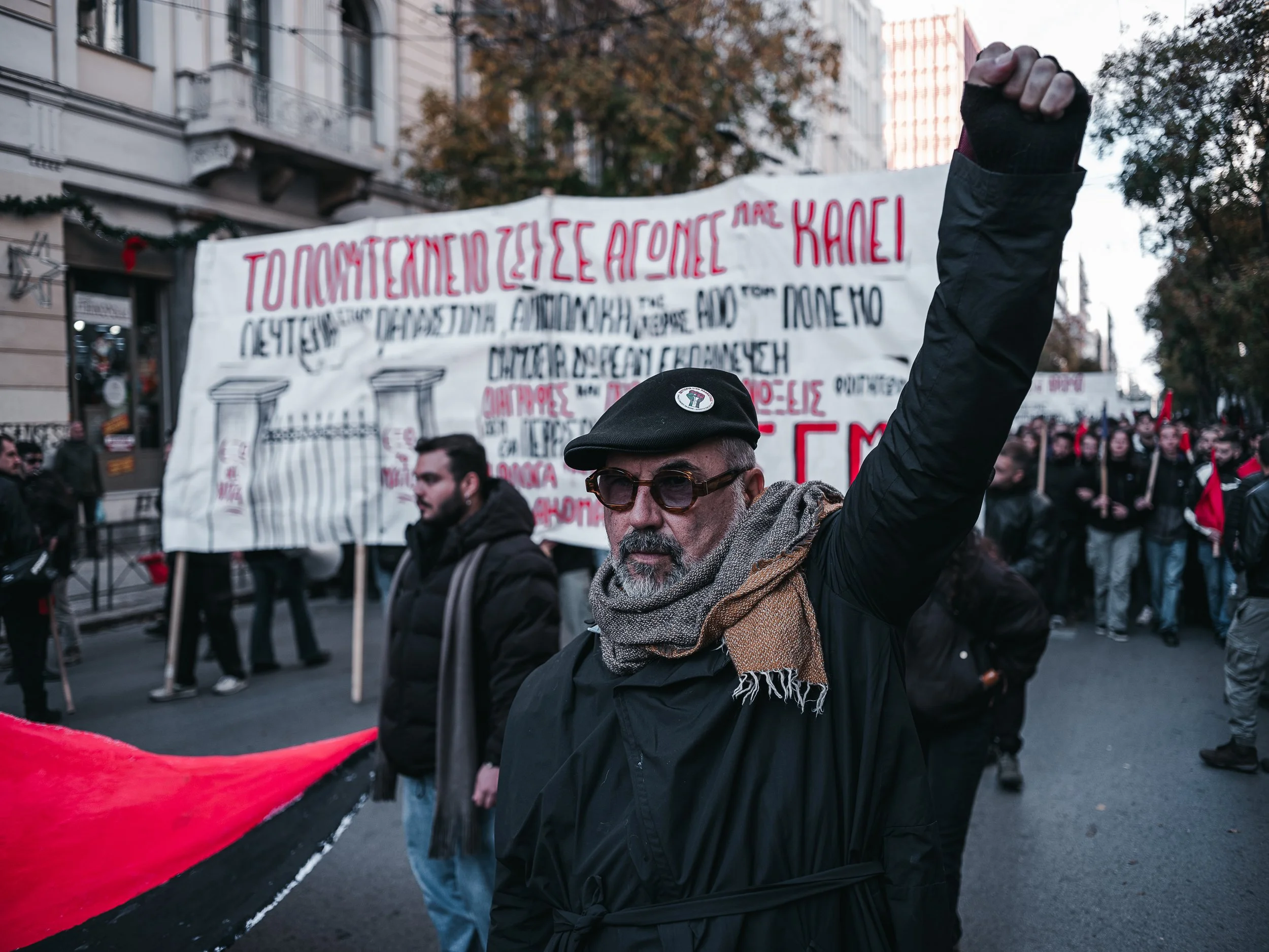 A man raises his fist while walking in front of a banner during a march in Athens, Greece on November 17, 2024. The event marks the anniversary of the 17 November Polytechnic Uprising, commemorating the 1973 student-led protest against the military d