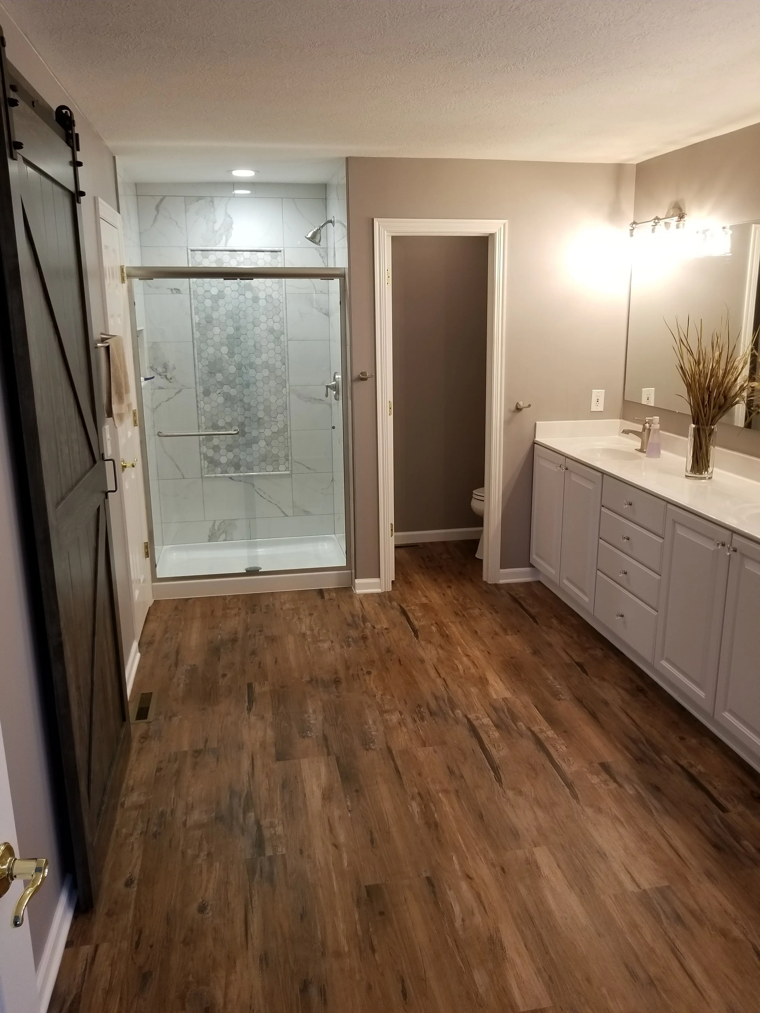Complete bathroom remodel with walk-in tile shower, wood flooring and vanity.