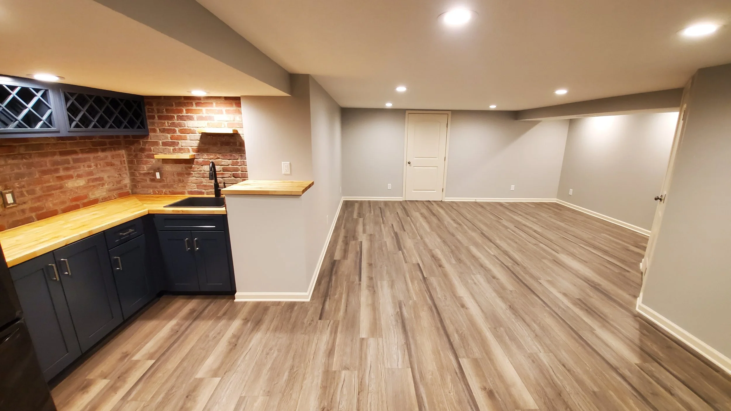 Basement redesign with custom wet bar, brick backsplash, new flooring and lighting.