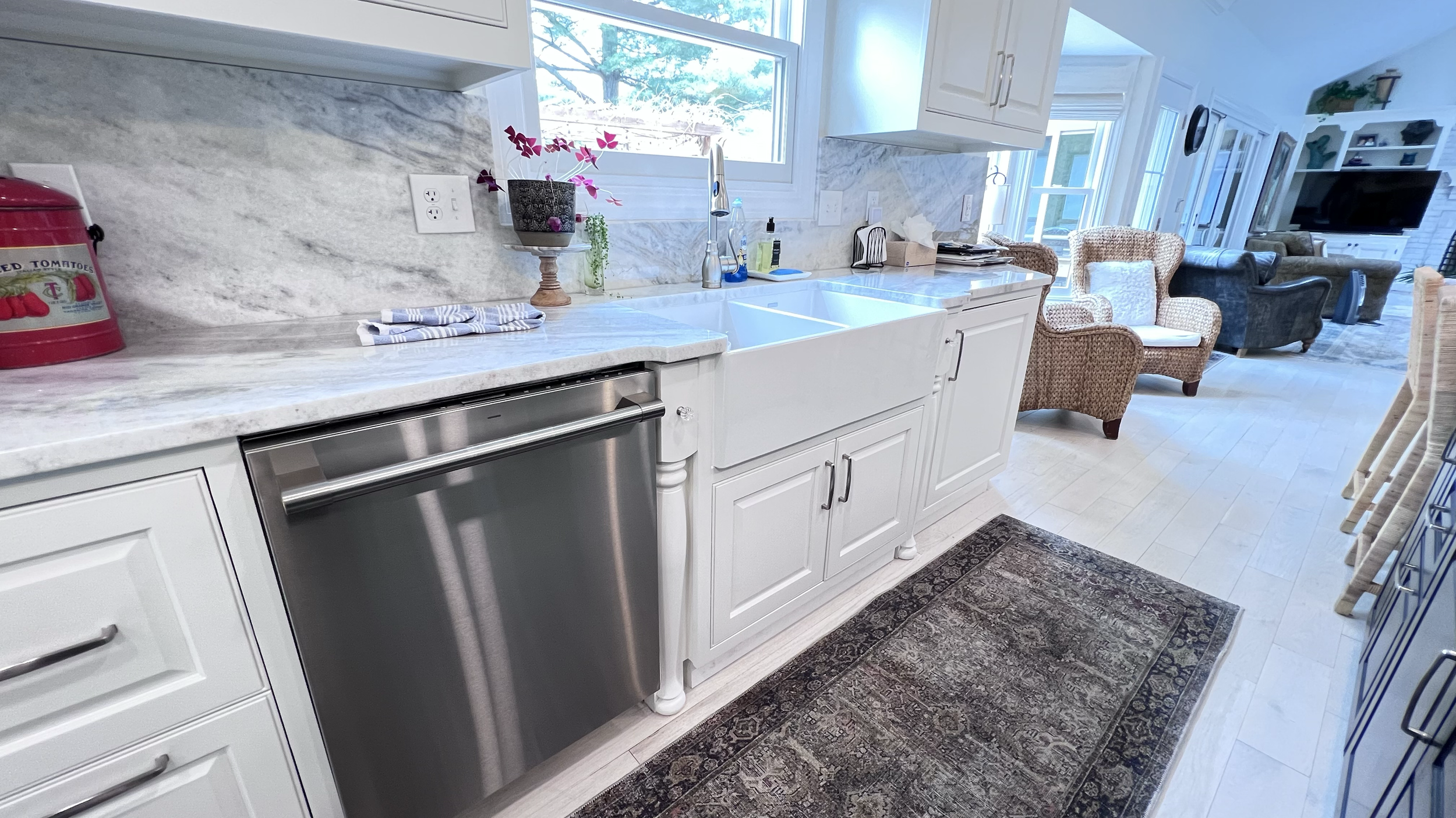 Kitchen remodel featuring new dishwasher, farm sink and granite backsplash.