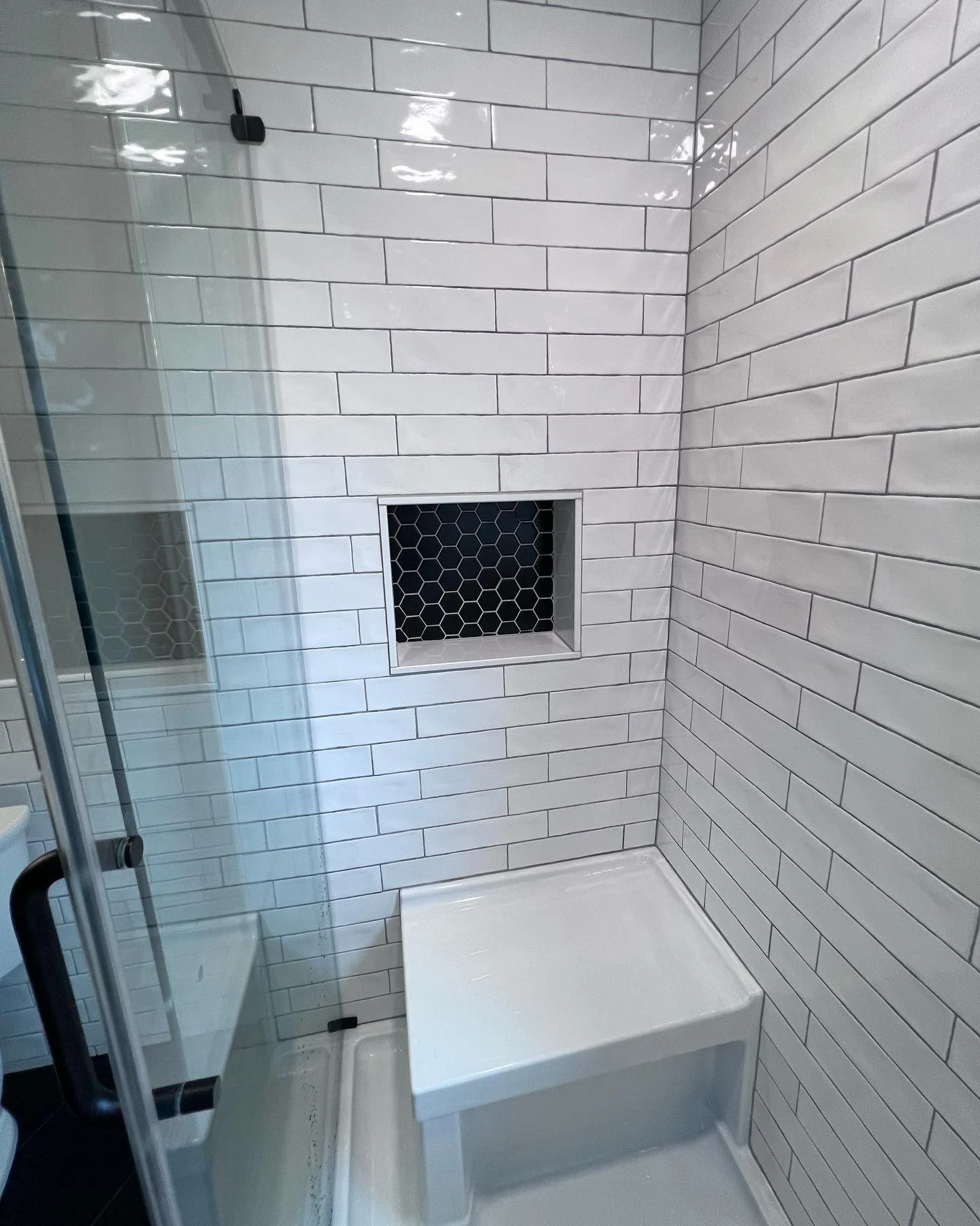 Subway tile shower renovation with large built-in shower bench.