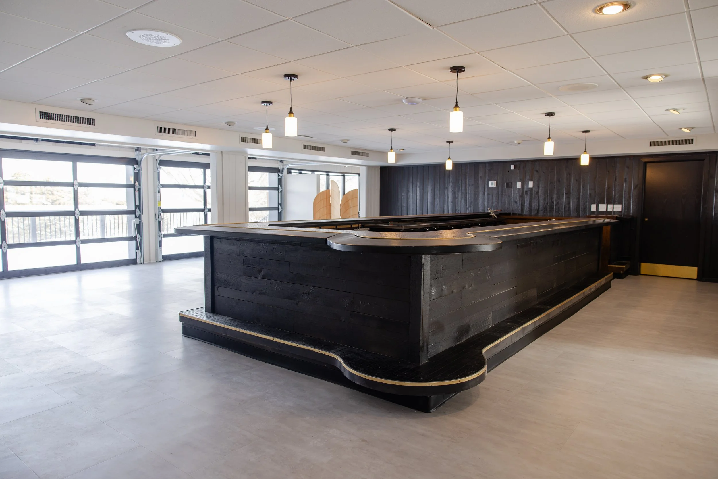 Cocktail bar with overhead garage doors that open to outdoor deck & lawn