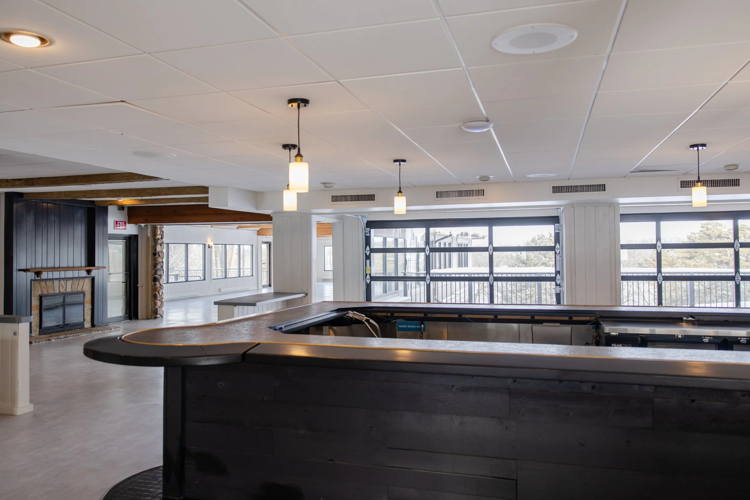 Cocktail bar with overhead garage doors that open to outdoor deck & lawn