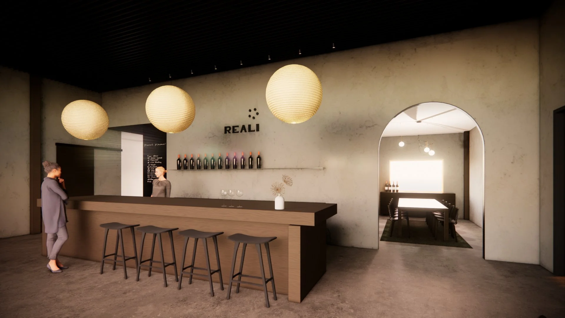 Interior of a modern wine bar or restaurant with a concrete wall, three large hanging paper lanterns, a bar counter with three stools, and a woman talking to a staff member behind the bar.
