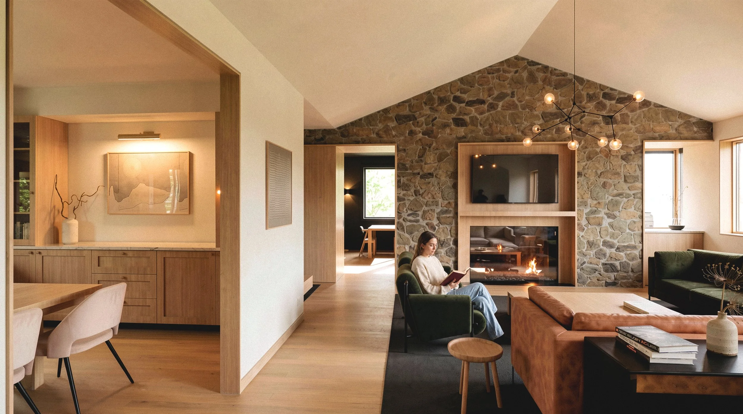 Minimalist modern living room featuring a stone fireplace and vaulted wood ceilings designed by Field Report.