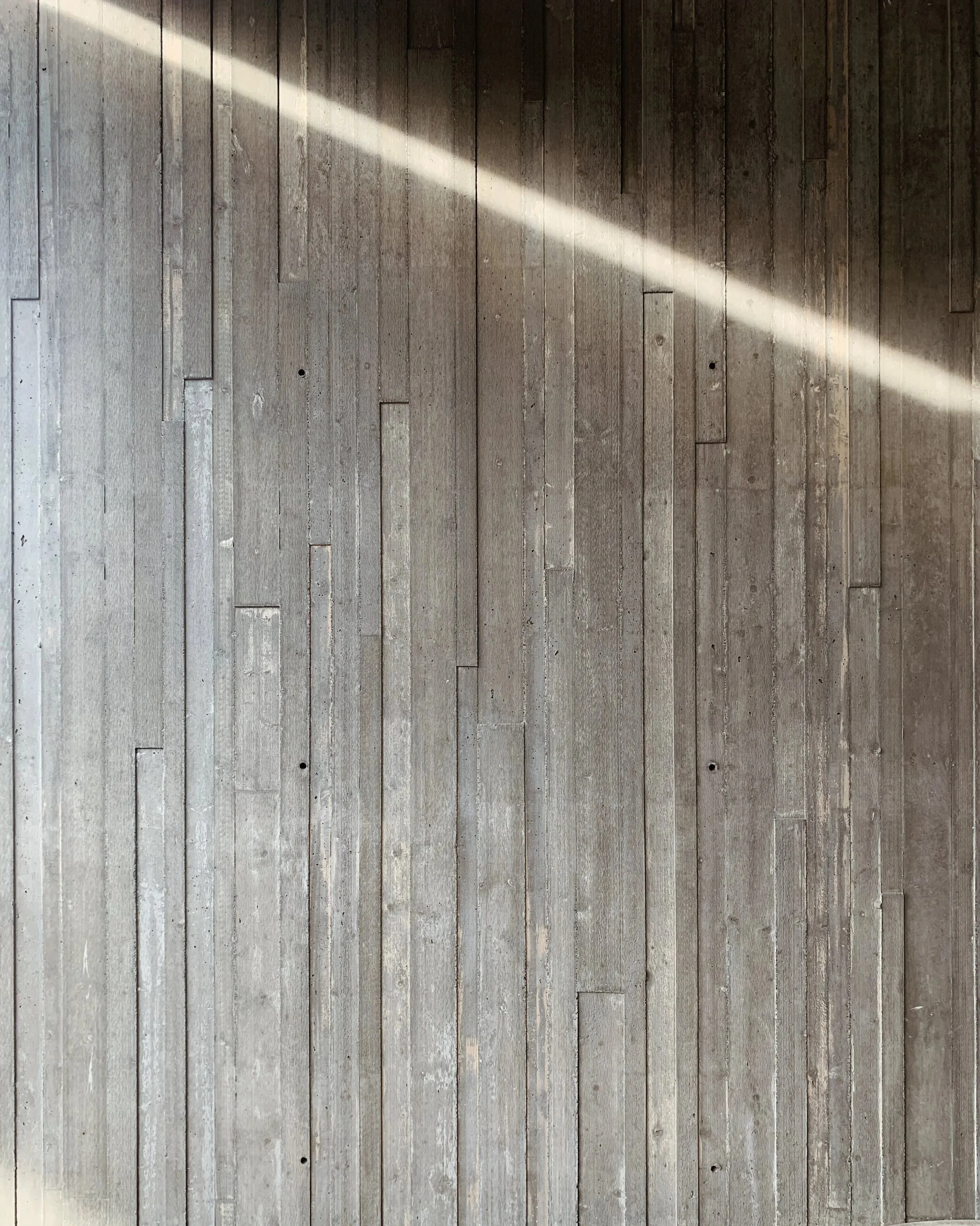 Architectural detail shot showing textured interior wall materials and natural sunlight.