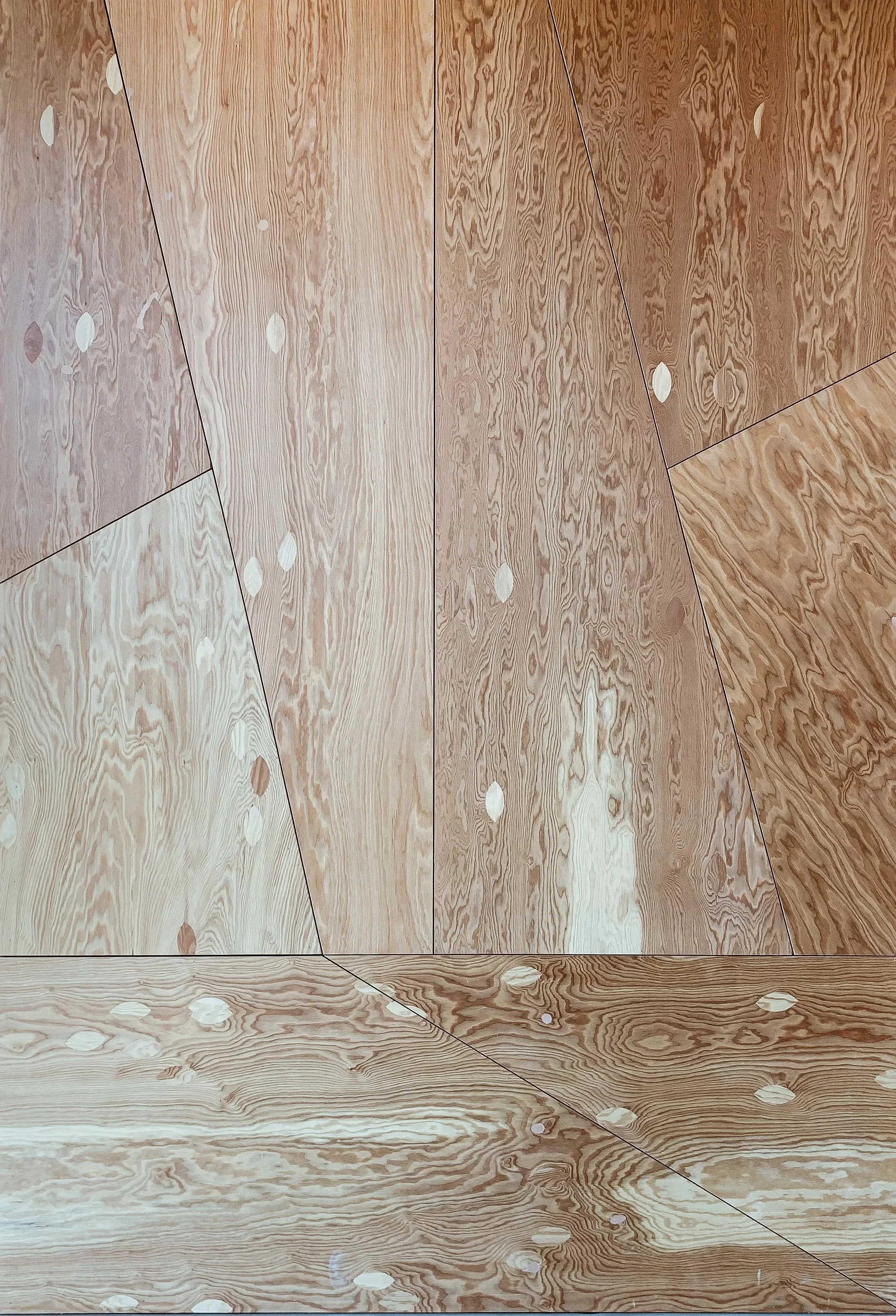 Close-up of a wooden floor with a geometric floor pattern created by different wood grains and color variations.