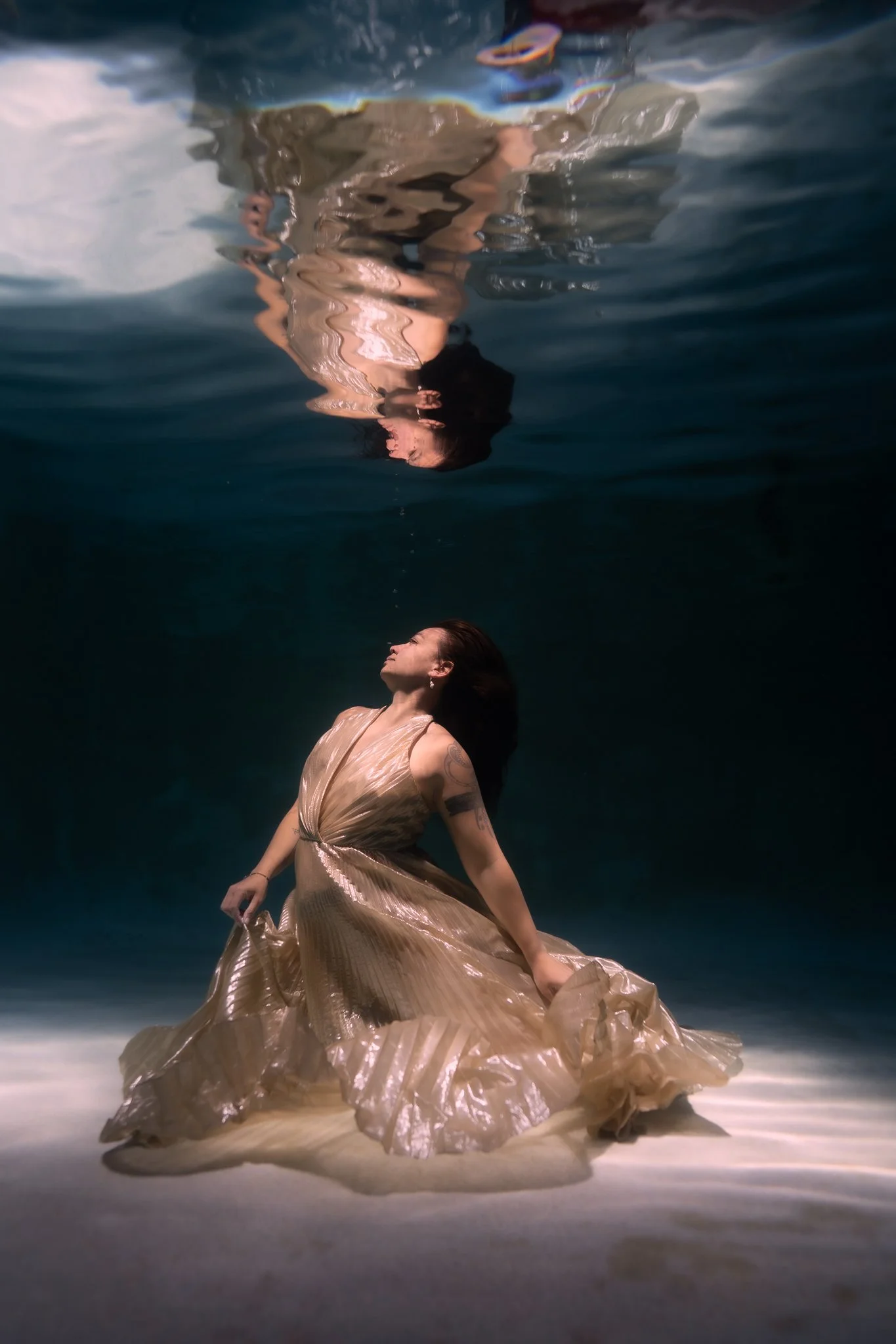 model poses in shallow underwater with reflection