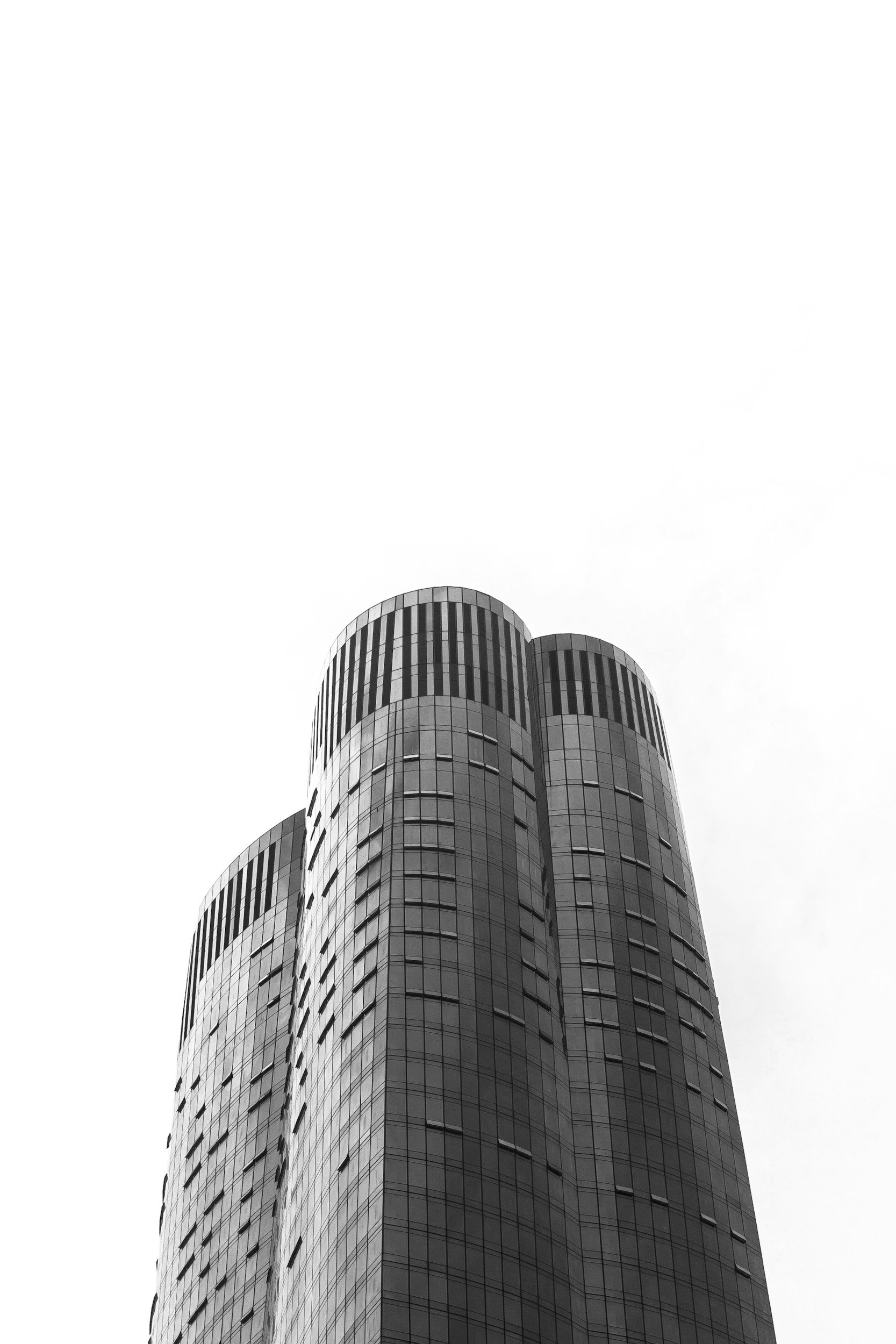 Black-and-white photo of a modern skyscraper with a rounded top against a pale sky.