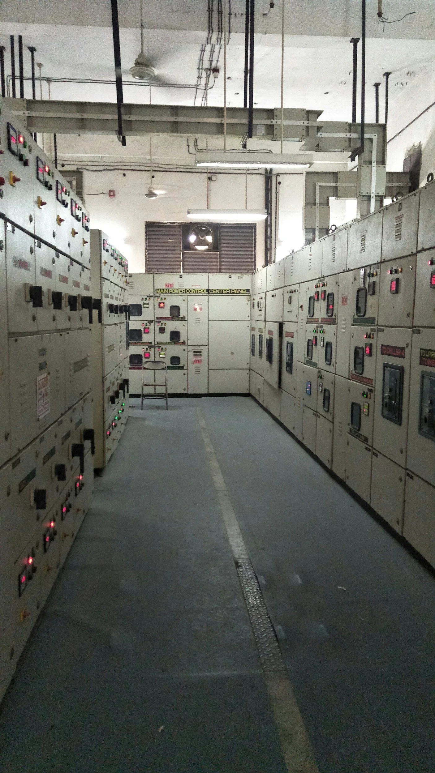 A room with rows of electrical control panels with various switches and lights.