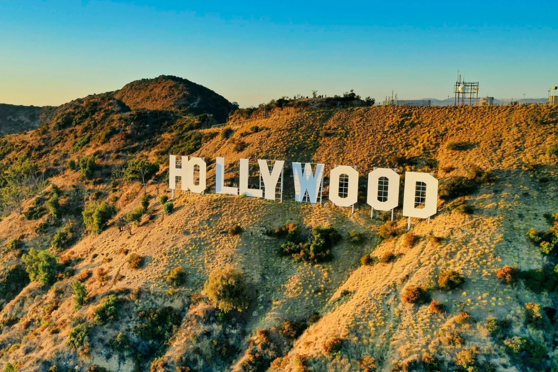 The Hollywood sign on a hillside in Los Angeles, California, during sunset with a clear blue sky.