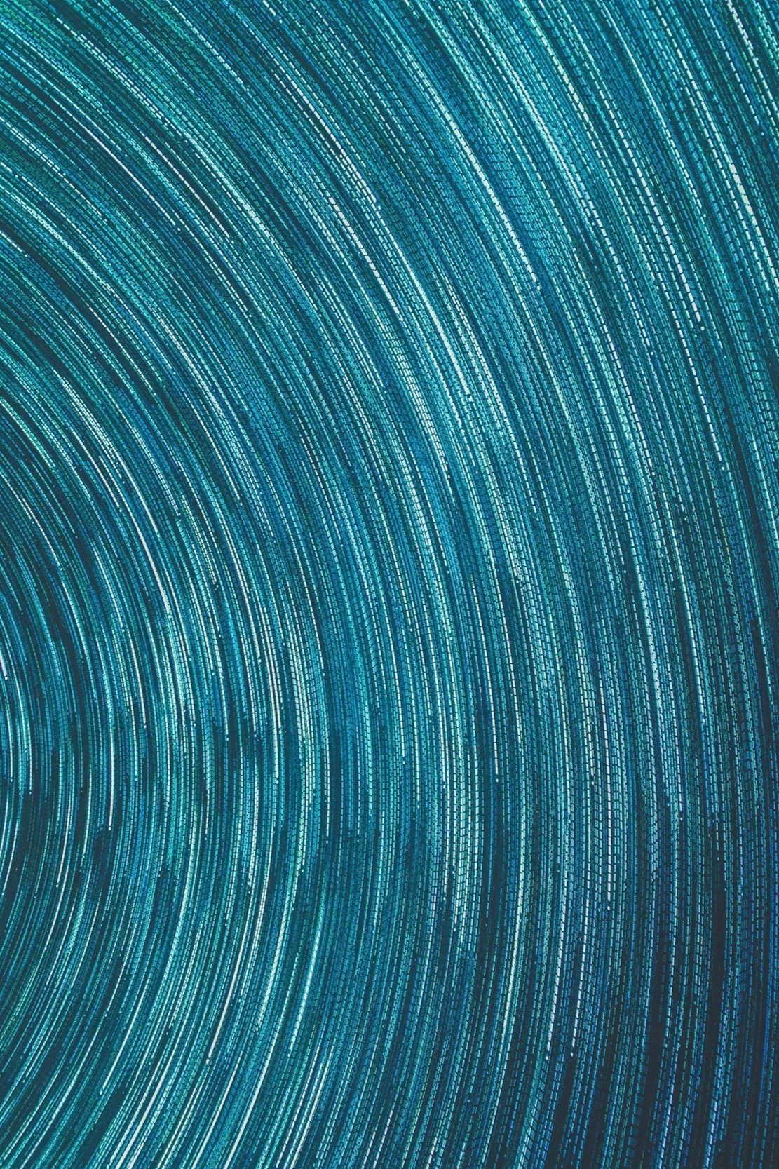 A digital abstract background featuring numerous curved lines made up of small glowing squares in shades of blue, teal, and white.