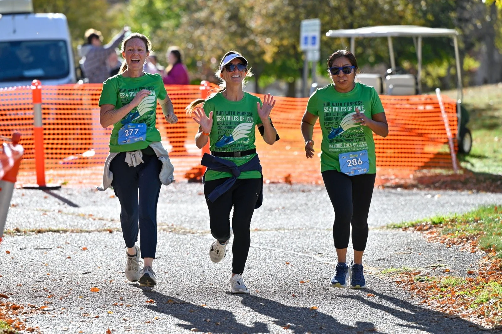 Three friends in matching green shirts run toward the finish together