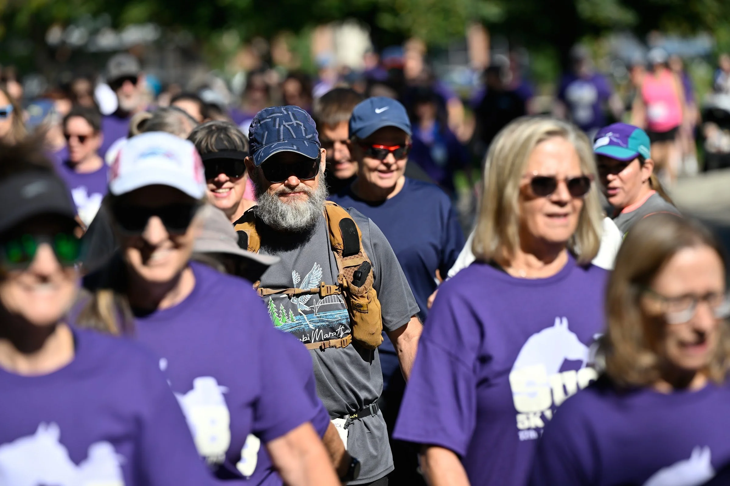 A crowd of SueB walkers and runners in purple shirts heading out together