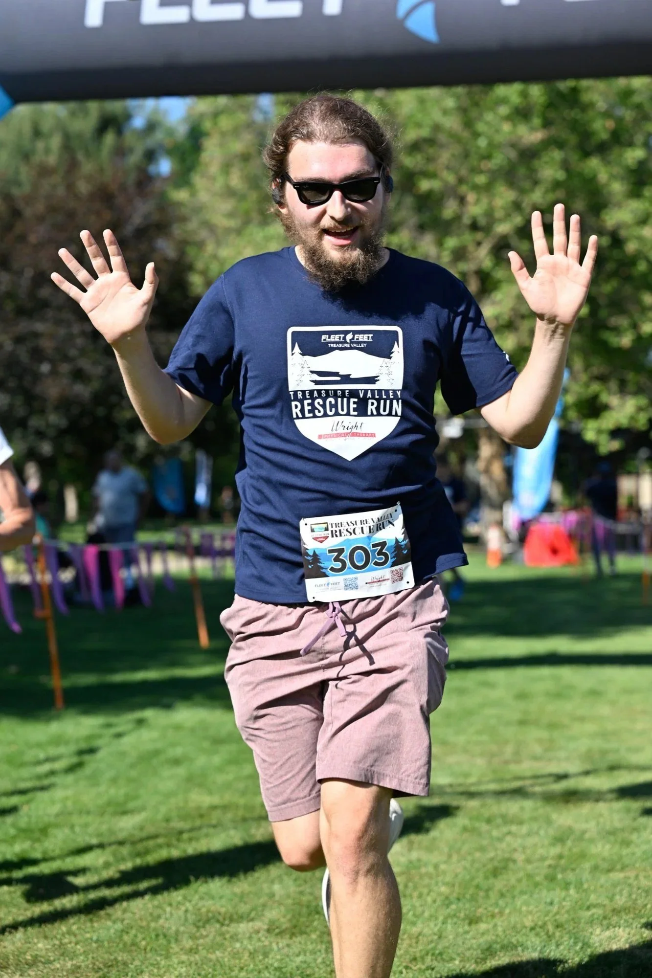 A runner throws both hands up as he crosses the finish at the Treasure Valley Rescue Run