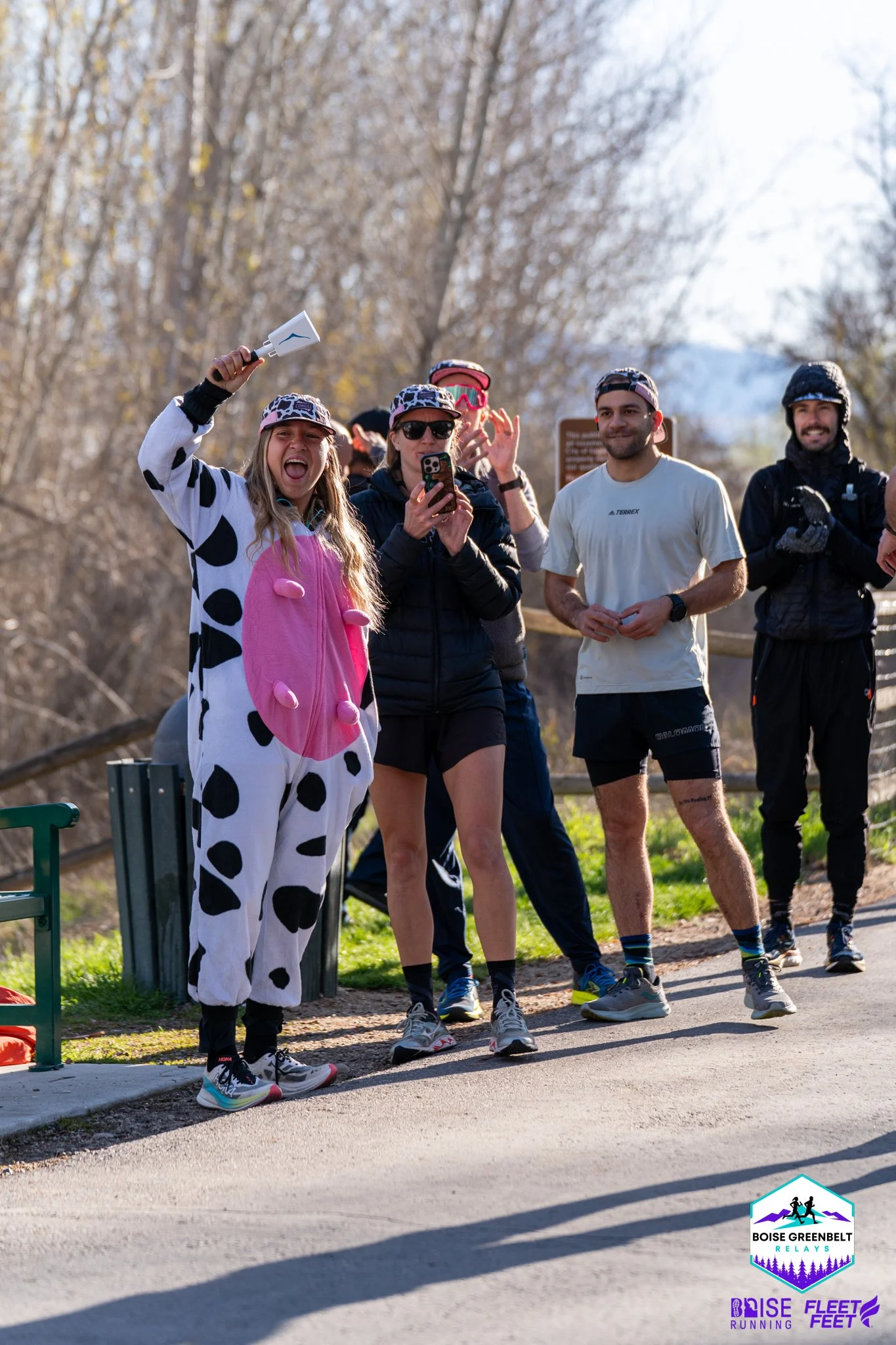 A relay team poses on the Greenbelt with one runner in a cow print costume