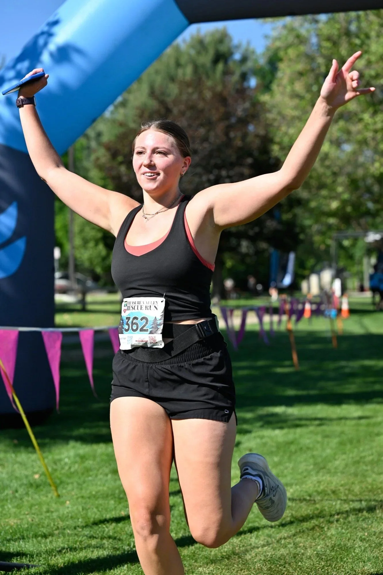 A runner celebrates with both arms up at the Treasure Valley Rescue Run finish
