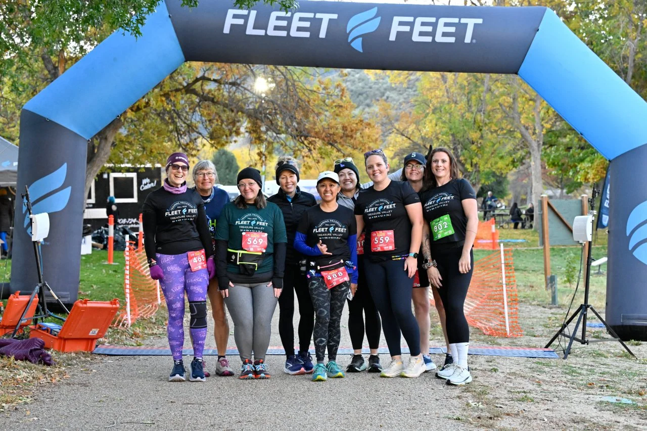 A run club posing together under the Fleet Feet arch at Idaho Running Day