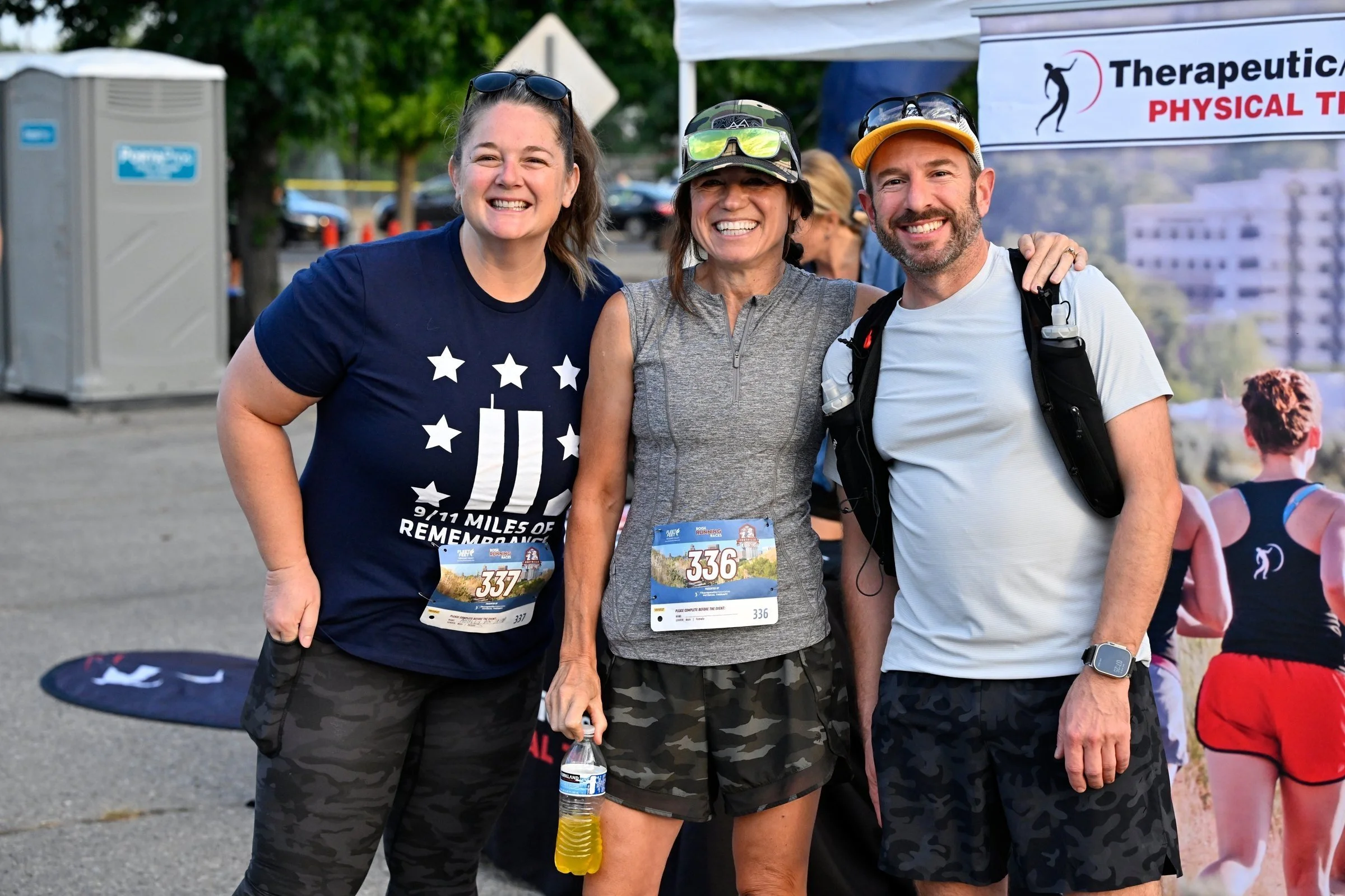 Three friends with their bibs smile together in the start area before the 2026 Foothills XC12K