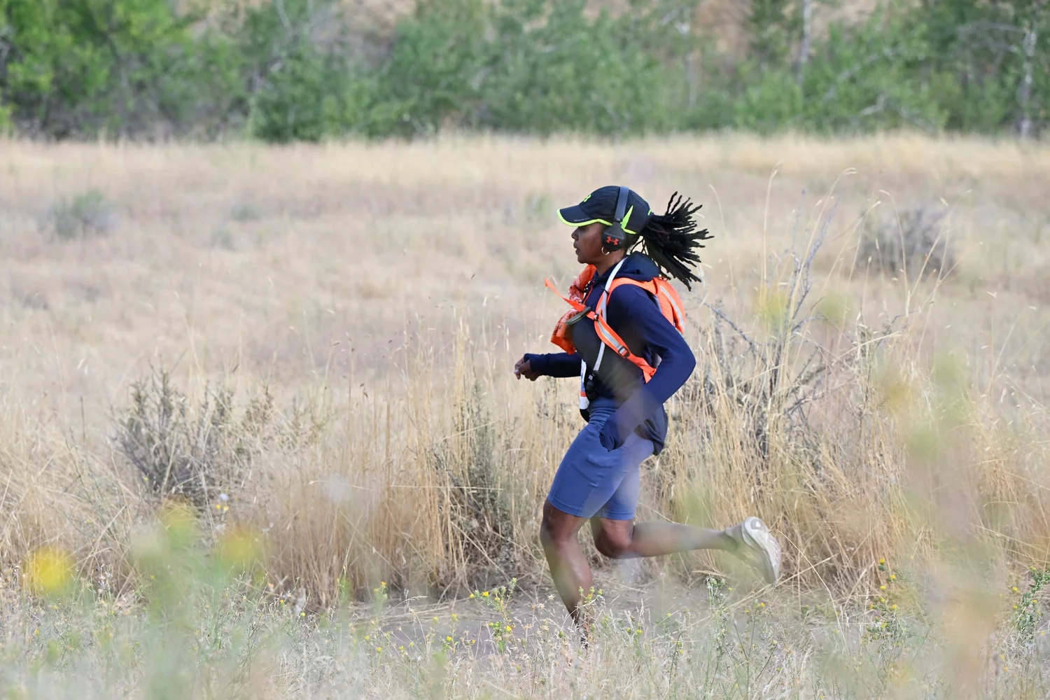 A runner strides through tall golden grass in the Boise foothills
