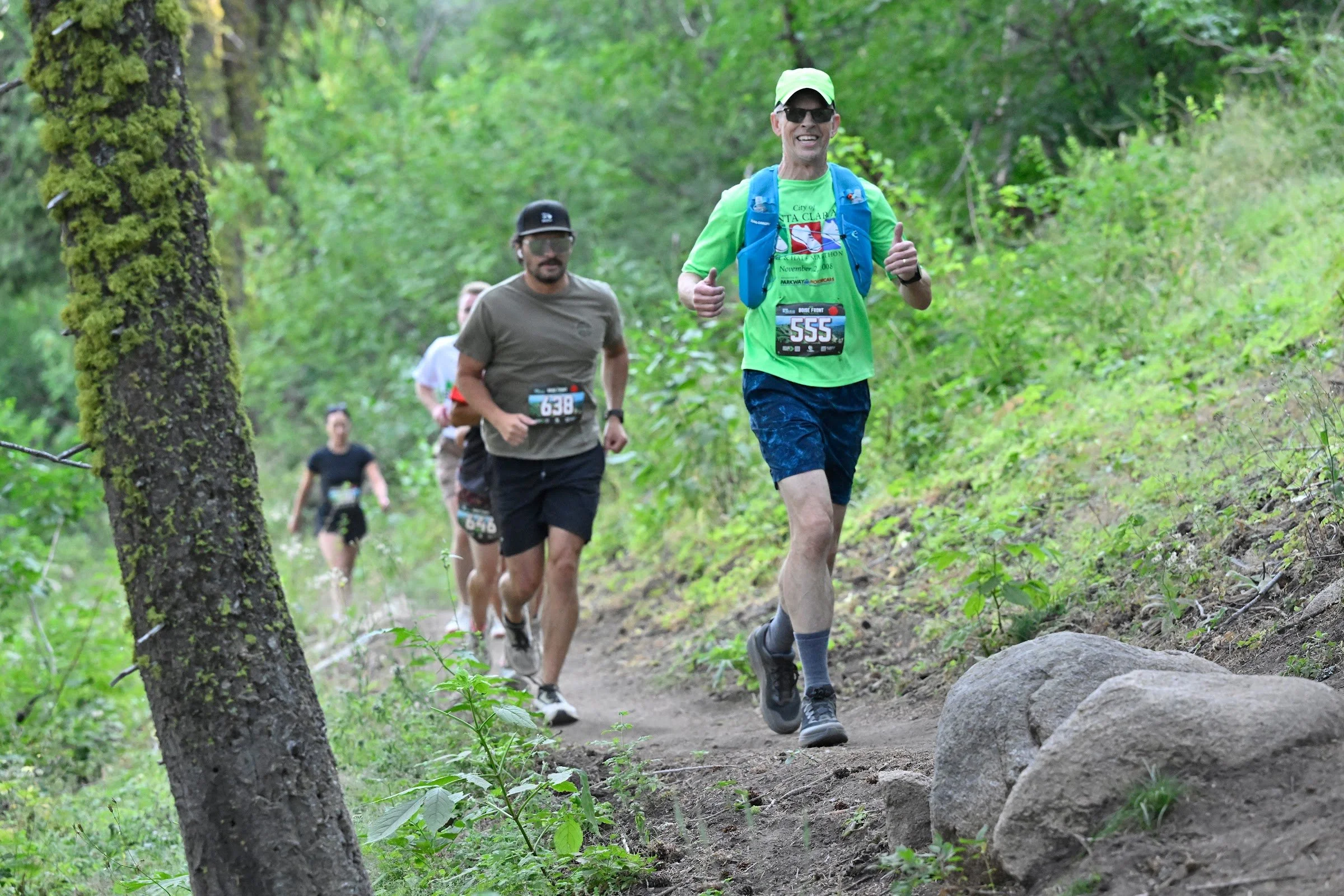 A line of trail runners climbs singletrack through the forest at Bogus Basin