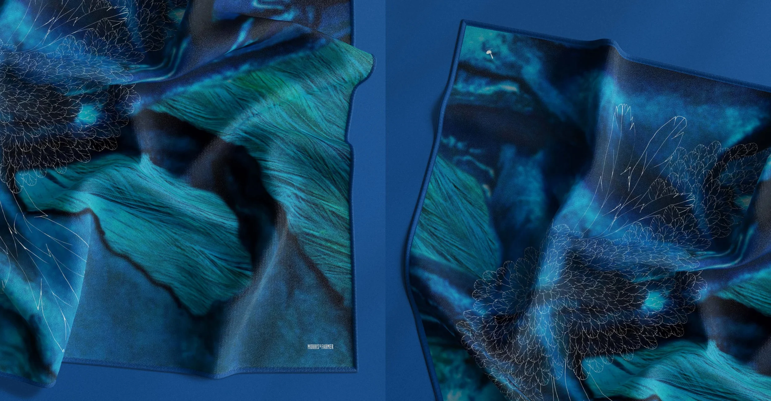 Close-up of a vibrant, blue-toned scarf with abstract floral and natural patterns, draped on a blue surface.