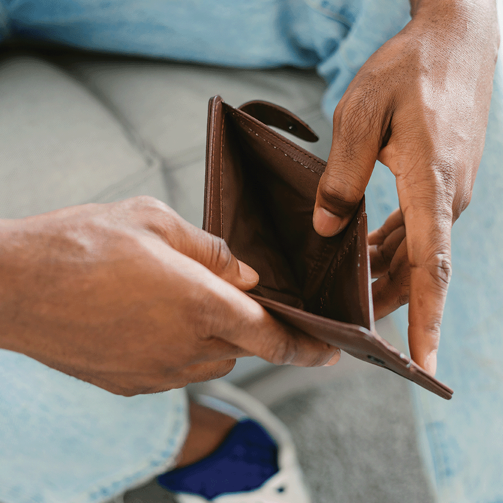 Person holding an empty brown leather wallet with no money or cards inside.