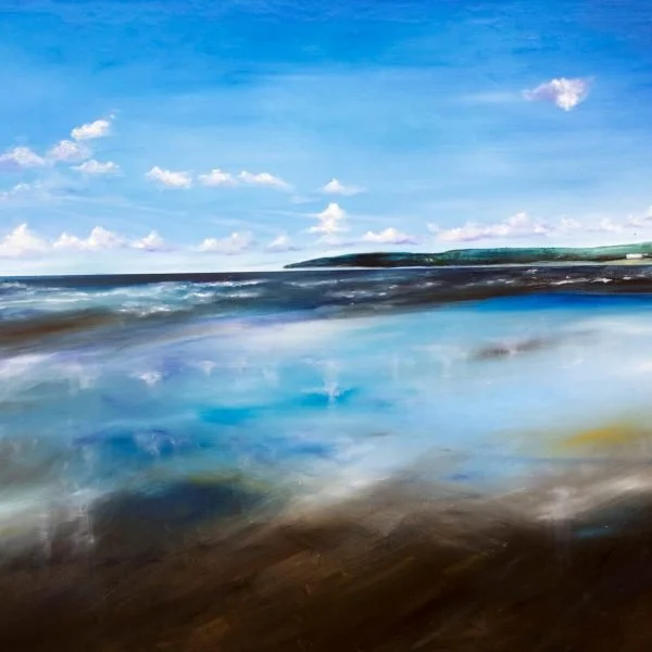 A serene ocean scene with blue sky, some white clouds, and waves crashing on the shore.